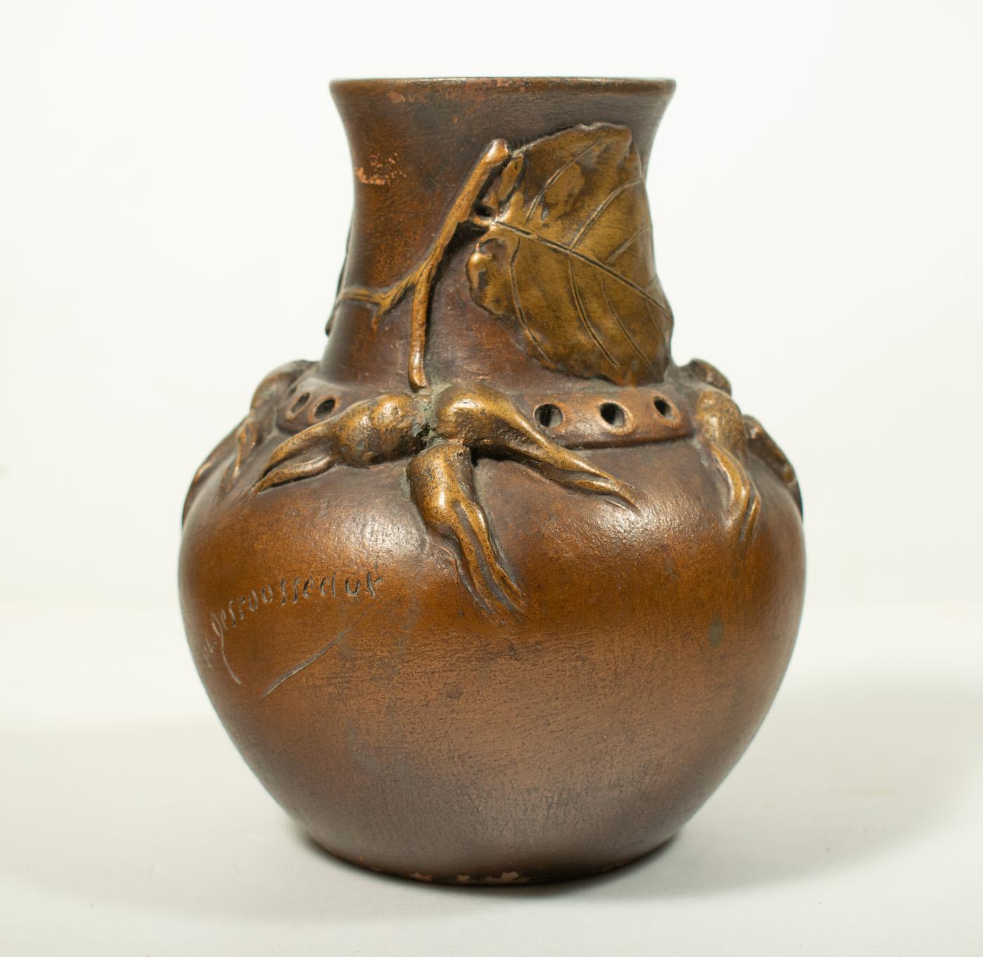 Henri-Laurent DESROUSSEAUX (1862-1906), L'Isle Adam: Art Nouveau vase in terracotta with an enamel finish, featuring a relief decoration of branches and hazel leaves with a bronze patina. Signed in the base. H: 17 cm.

Henri-Laurent Desrousseaux