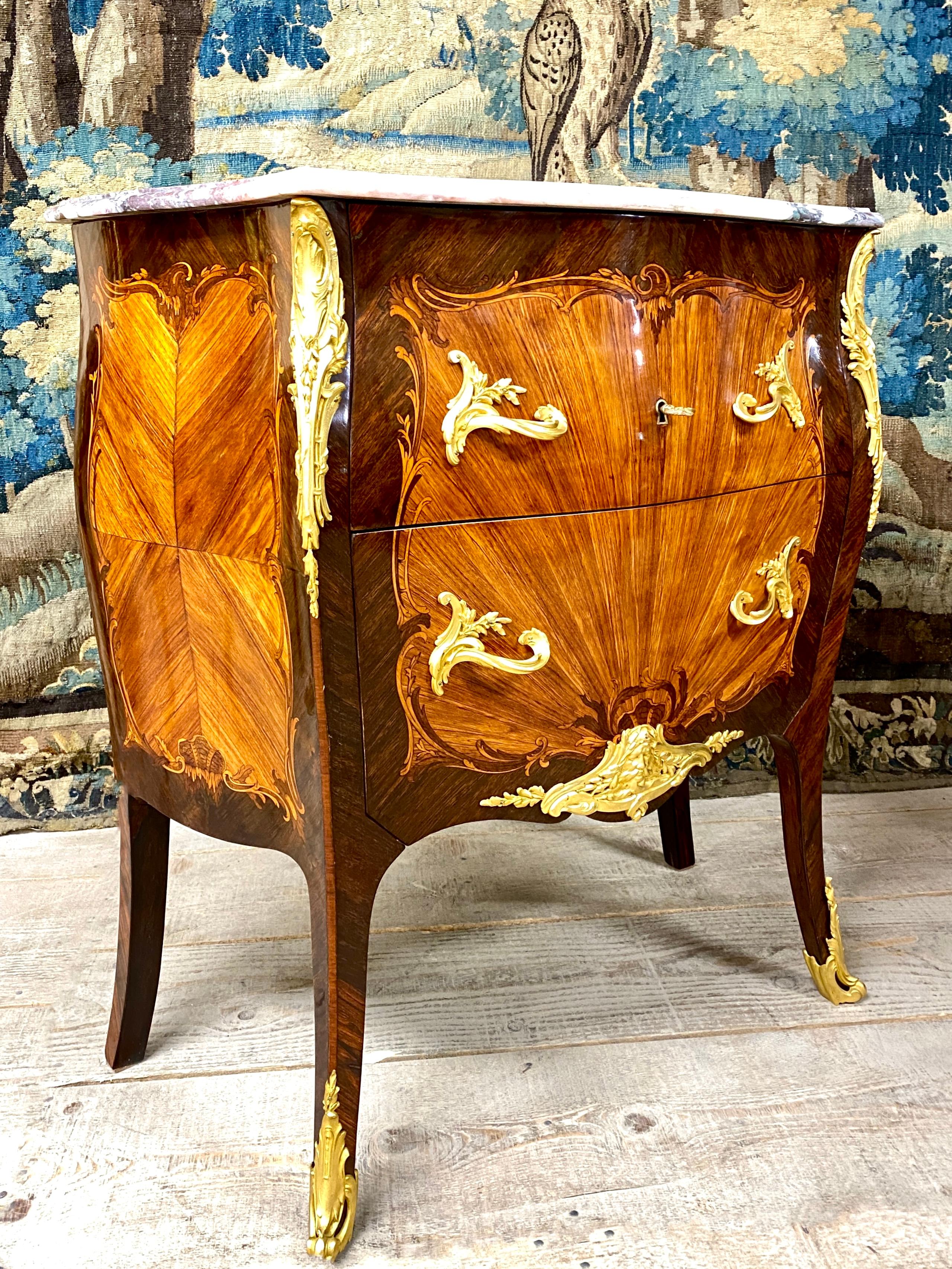 Chest of drawers between two opening by two drawers without curved crosspiece. It is in marquetry of kingwood on a rosewood background, decorated with intertwined foliage and shells on all sides. Louis XV style, it rests on four curved legs, and is