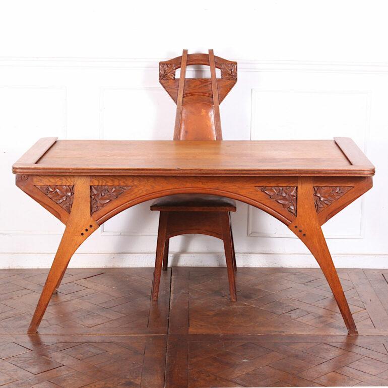 An elegant French Arts and Crafts period writing desk by French designer Henri Rapin. Striking arched form to the legs and up through the apron, which is fitted with five drawers. Original hammered metal hardware and carved ivy motif to the reverse.