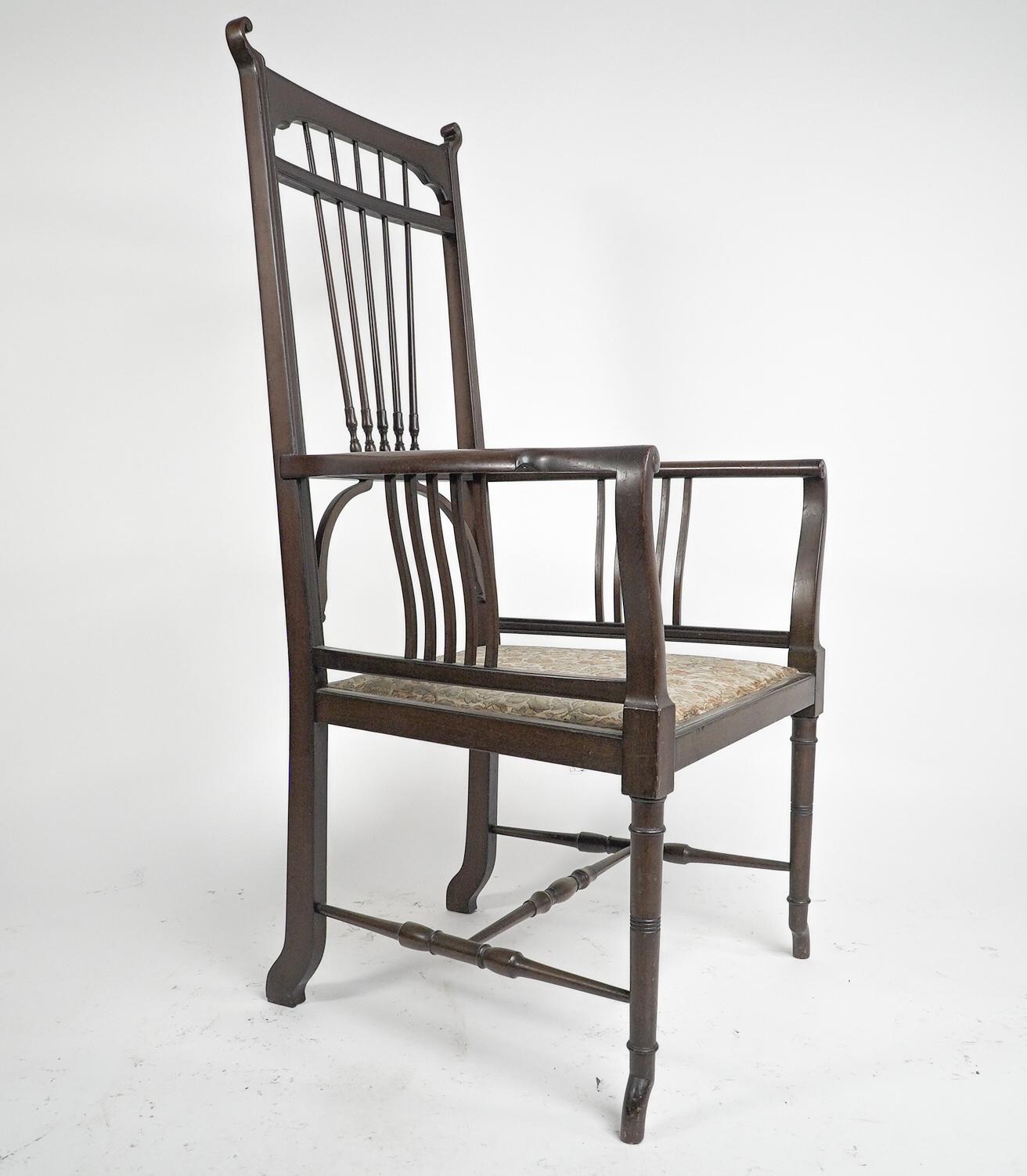 Henry Batley Attributed. An Aesthetic Movement walnut armchair with sinuous touches, curled finials, and a spray of elongated turned details to the back. The shaped arms have curvaceous supports below them uniting the seat, with fine ring turned