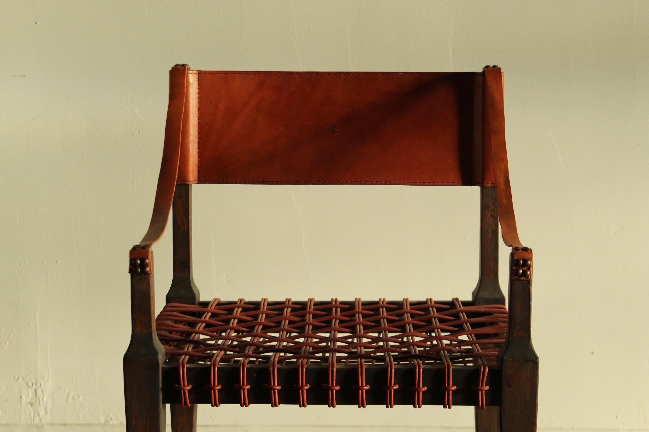 A stunning and rare, vintage armchair by Henry Beguelin in gorgeous whiskey colored leather. Thick leather back support with small woven bear detail. Thin slung leather strap arms. Woven leather cord seat. Tapered legs. Super regal from every angle,