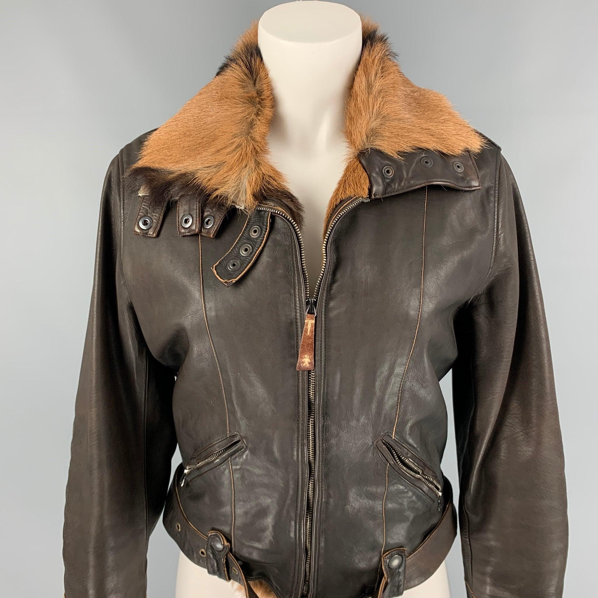La veste HENRY BEGUELIN est proposée en cuir chamoisé marron et tan et présente un style moto, un col en fourrure, des empiècements matelassés aux coudes, des poches zippées, des boutons-pression et une fermeture à glissière. Fabriquées en