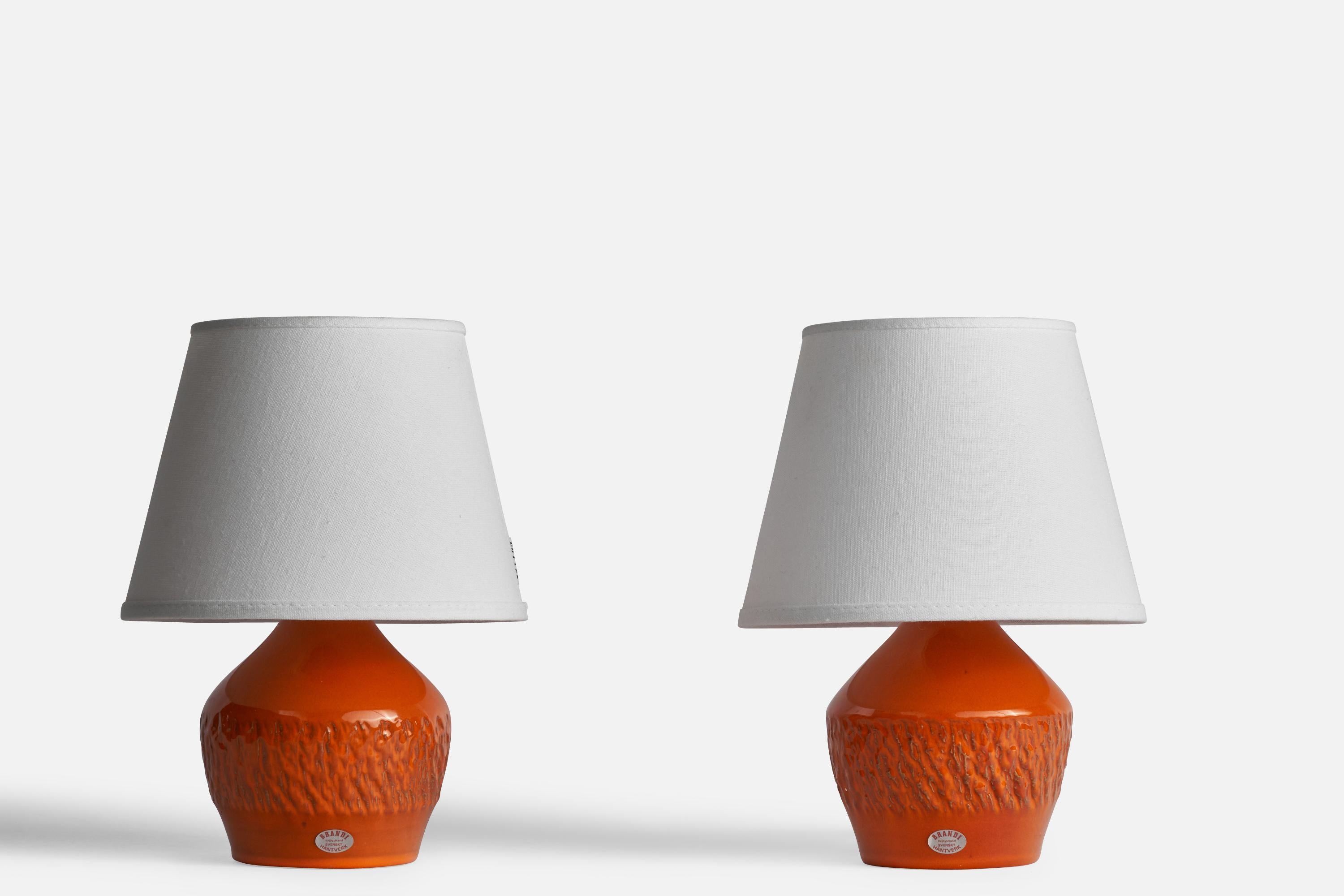 A pair of orange-glazed and incised table lamps designed and produced by Henry Brandi, Vejbystrand, Sweden, c. 1960s.

Dimensions of Lamp (inches): 8.1” H x 4.75” Diameter
Dimensions of Shade (inches): 5.25” Top Diameter x 8” Bottom Diameter x 6”