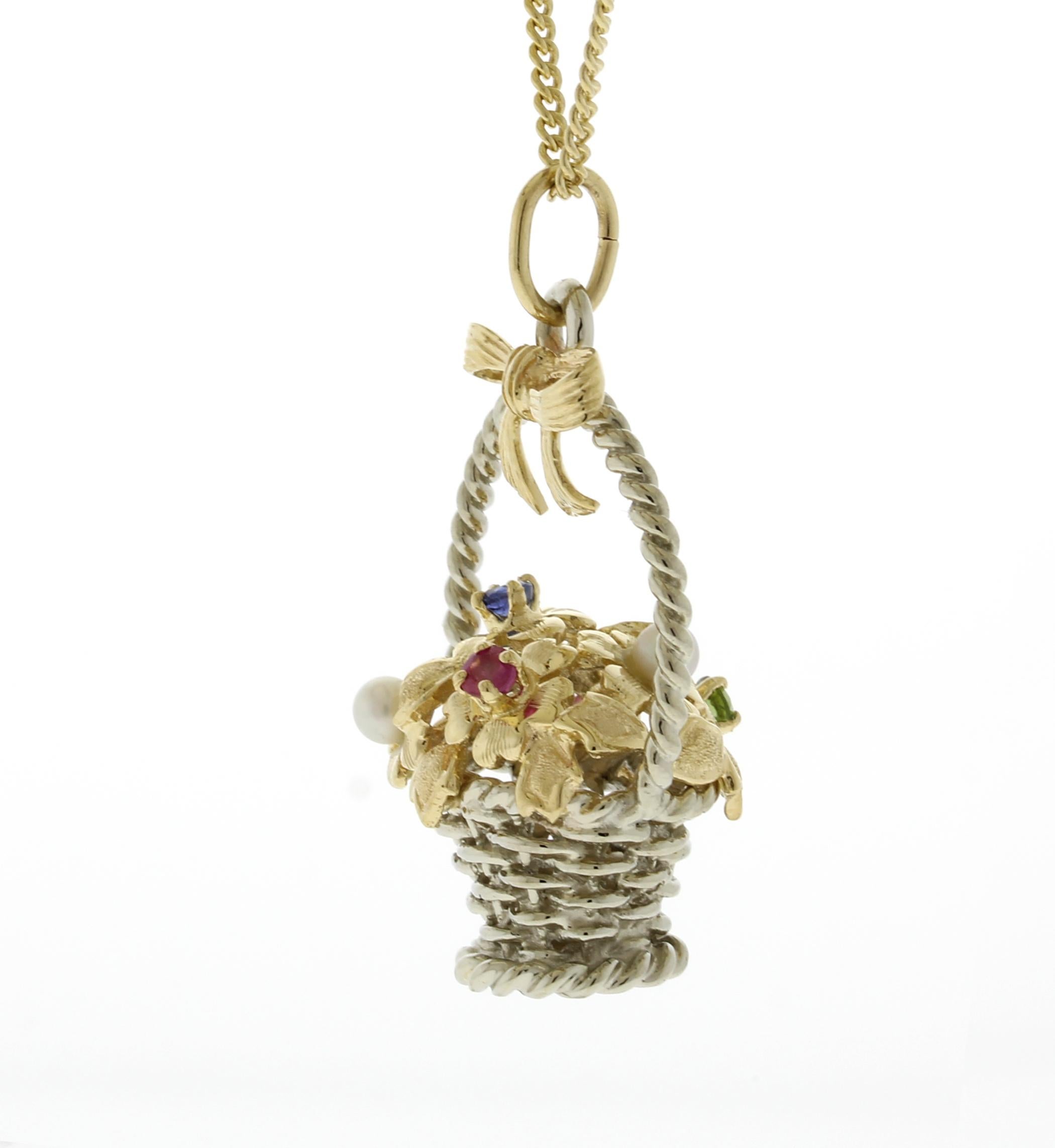 Questo ciondolo a 14kt presenta una combinazione di oro giallo e bianco, oltre a 2 zaffiri rosa, 1 zaffiro blu, 1 peridoto e 2 perle. Il ciondolo è accompagnato da una catena di 20 pollici e pesa complessivamente 10,8 grammi. È firmato con Copyright