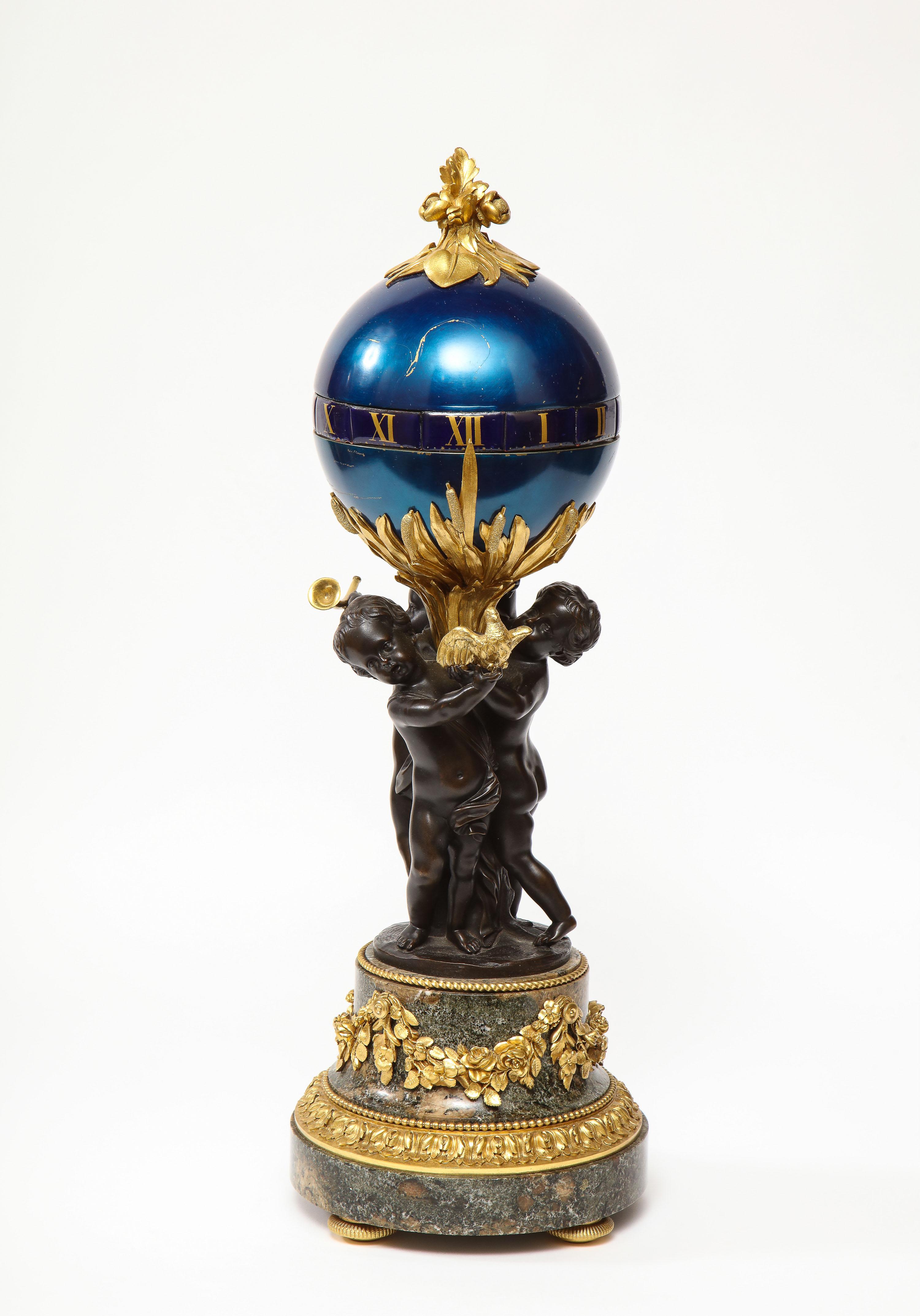 A French gilt and patinated bronze, marble, and enamel annular dial clock by Henry Dasson, Paris, 1891.

Bronze floral finial atop a blue enameled globe with gilt Roman numeral porcelain annular dial, three patinated bronze cherubs mounted to a