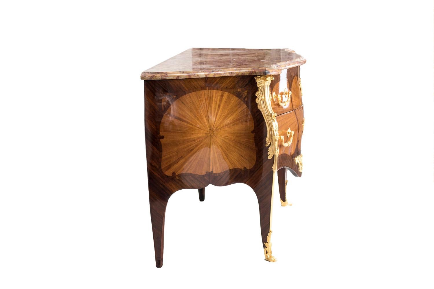 Louis XV style commode, bulged and opening with two front drawers without crosspiece and standing on cabriole legs. The furniture body is inlaid in his center with rosewood marquetry arranged in fan-shaped and framed with kingwood. Two little