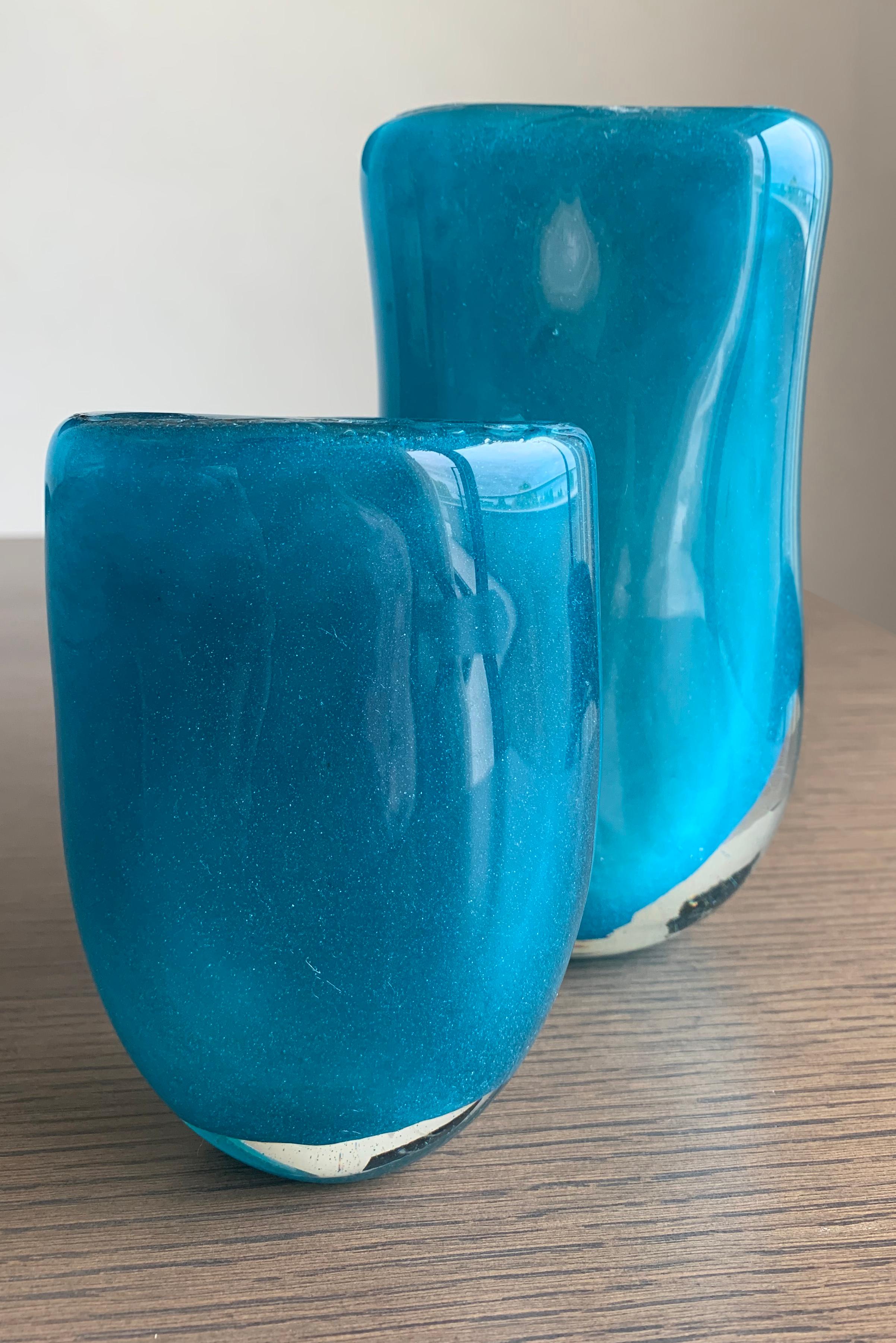 A stunning duo of handcrafted turquoise glass vases by Belgian glass master Henry Dean. 

This set includes one small and one medium-sized vase, each showcasing Dean's exceptional glassblowing skills and mastery of colour application.
Made using