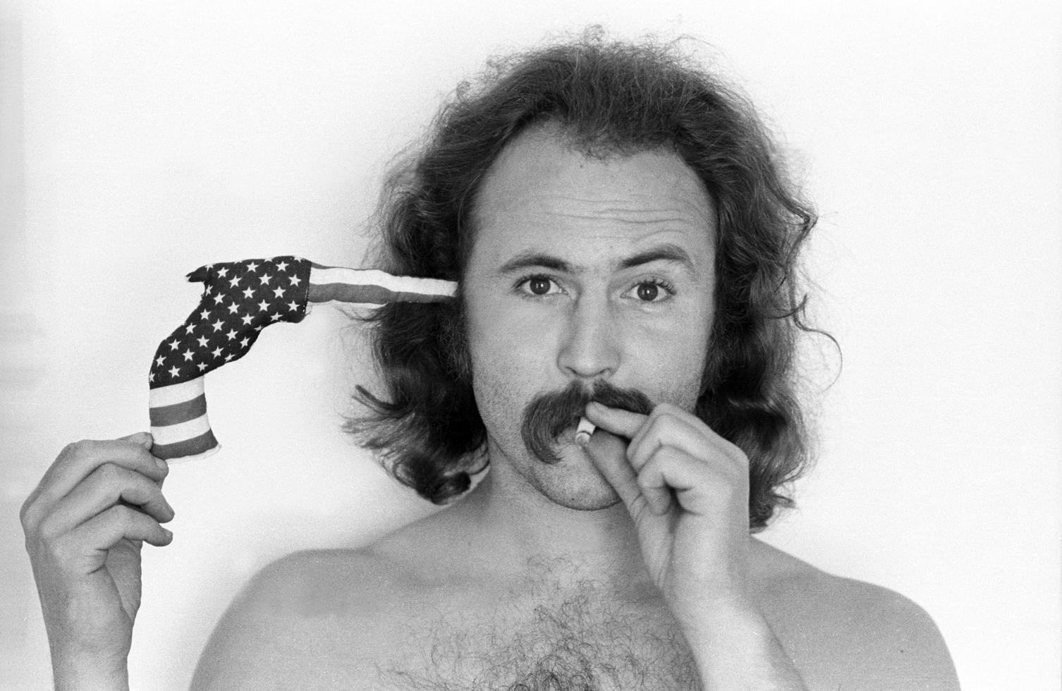 Henry Diltz Black and White Photograph - David Crosby, "Flag Gun", 1970
