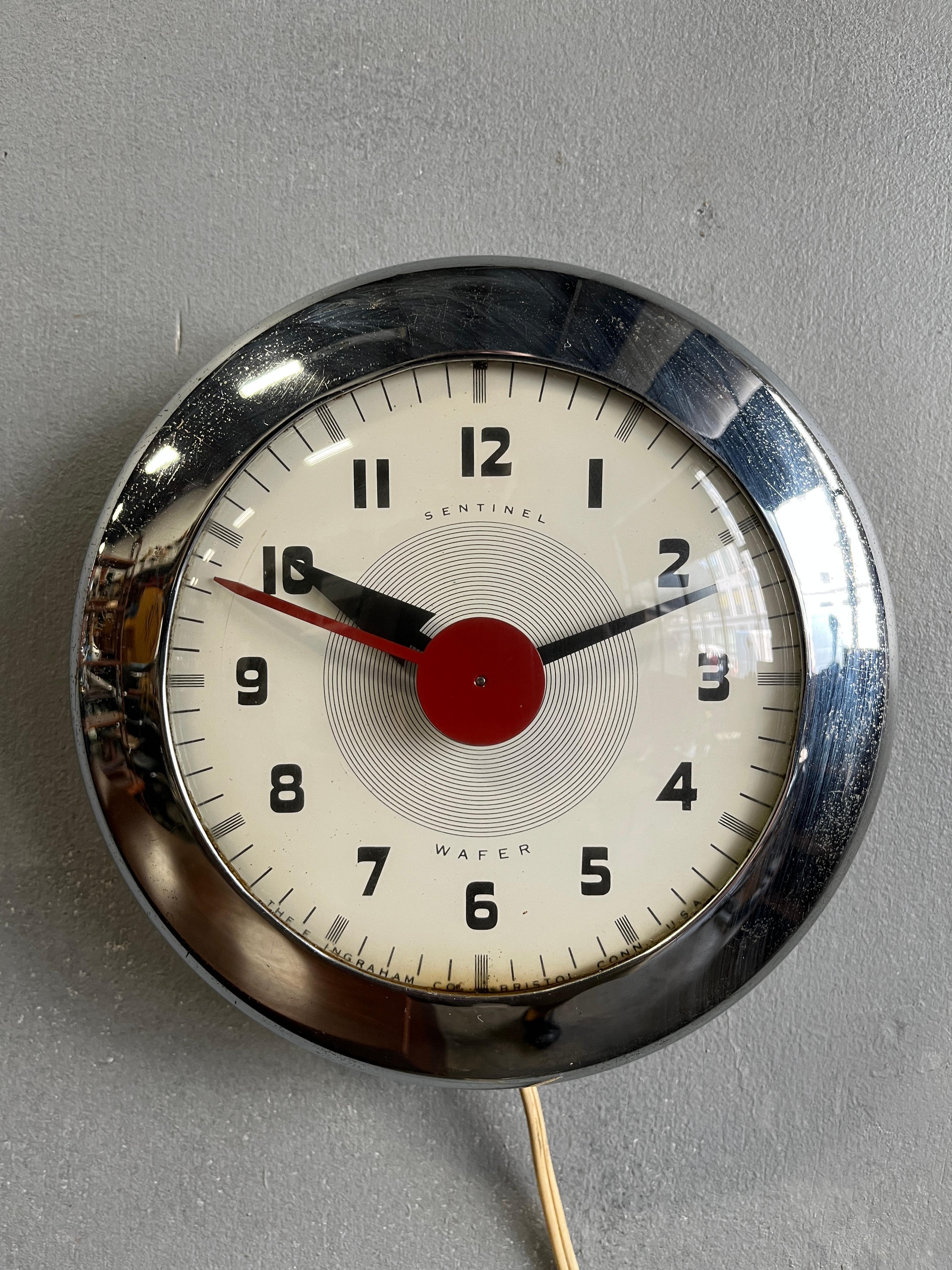 Grafisch ansprechende Chromwanduhr mit klassischen 50er-Jahre-Details. Das schwungvolle Zeigerwerk dieser wunderschönen Uhr wurde von einem der größten Industriedesigner dieses Jahrhunderts entworfen.