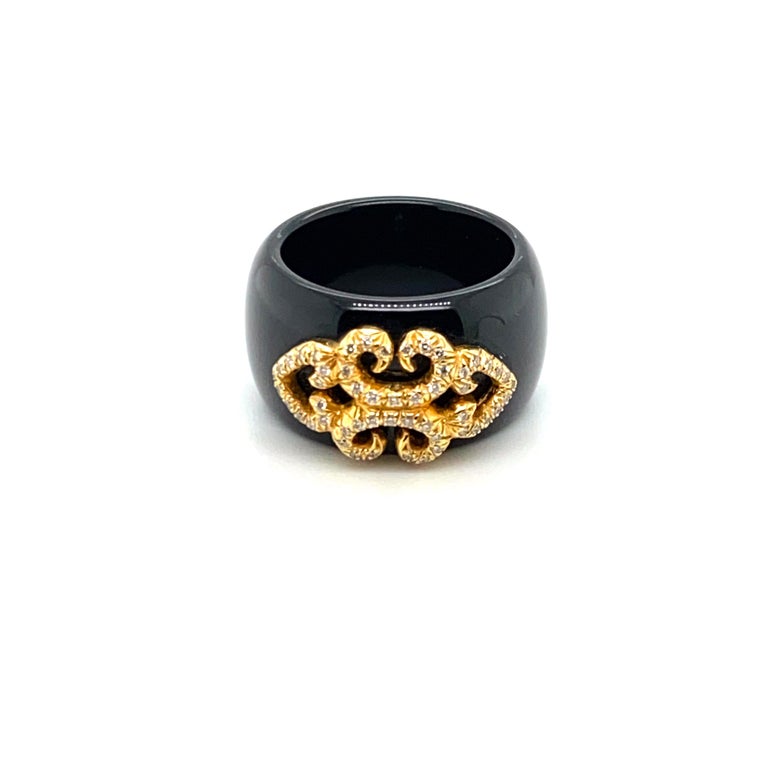 This Henry Dunay ring is composed of polished black jade with two inlaid sections of yellow gold - the raised diamond setting attached via a screw mechanism, and the signature plaque inlaid directly into the jade itself.  The ring features 52 round