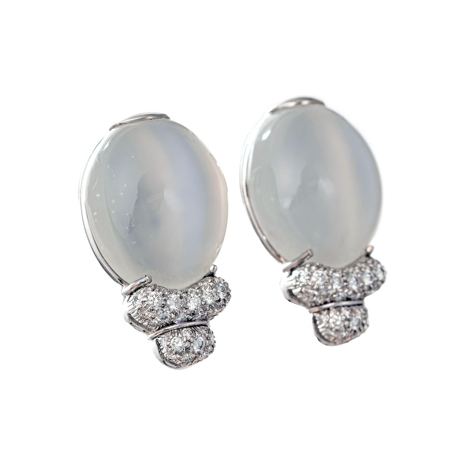 Oval-shaped cabochon white cat's eye moonstone earrings with pavé-set diamond accents at base, set in platinum. 86 diamonds weighing approximately 2.00 total carats. Posts with white gold omega-style clip backs. Signed Henry Dunay with serial number