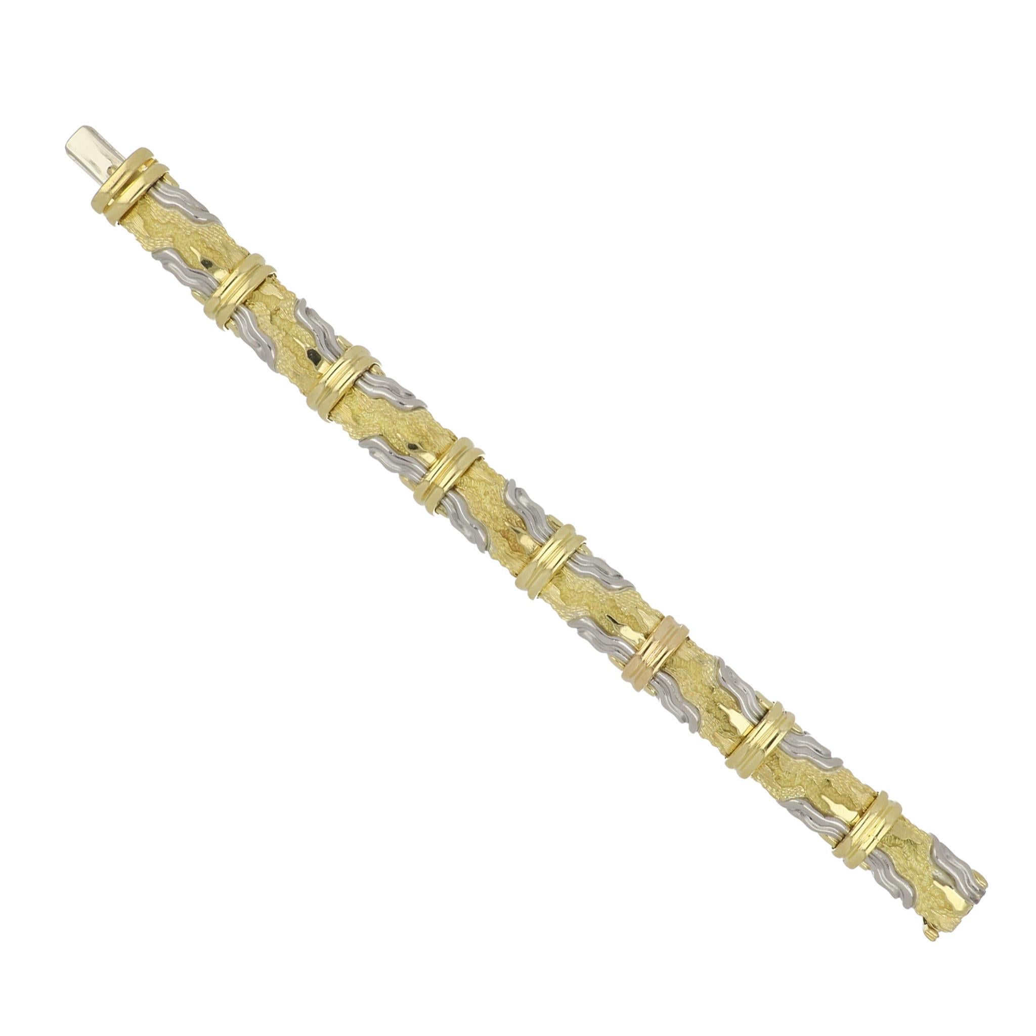 An estate Henry Dunay platinum and 18K yellow gold bracelet from the Cinnabar collection.  It has eight plaque like links with a textured design.  It measures 7 inches in length and 1/2 inch wide.  Circa 2000.
