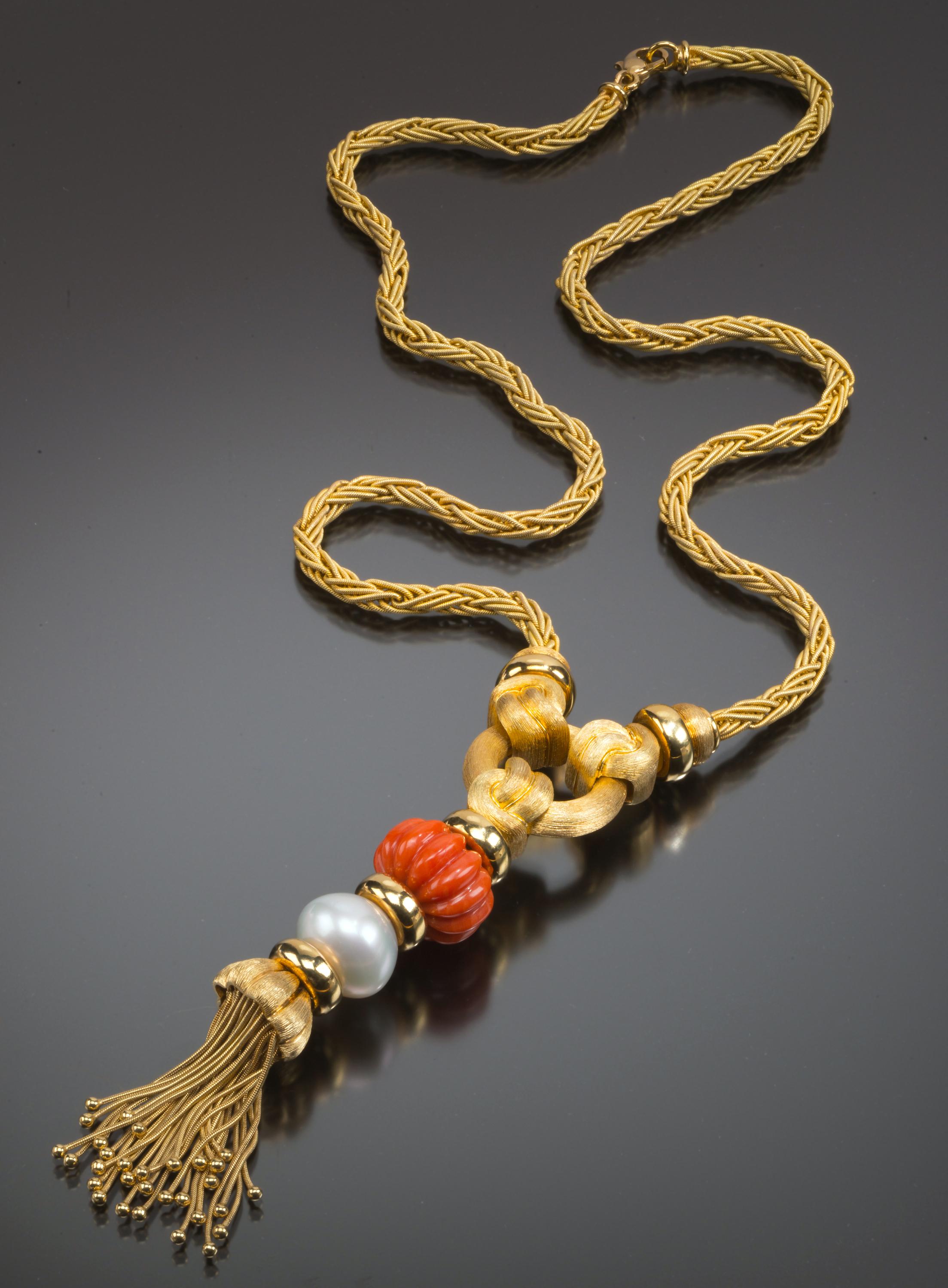 A weighty 18k gold rope twist chain suspends an intricate tassel pendant composed of a fluted coral bead and an off-round cultured pearl in this dramatic sautoir necklace from American jeweler Henry Dunay. Dunay’s famous Sabi surface technique can