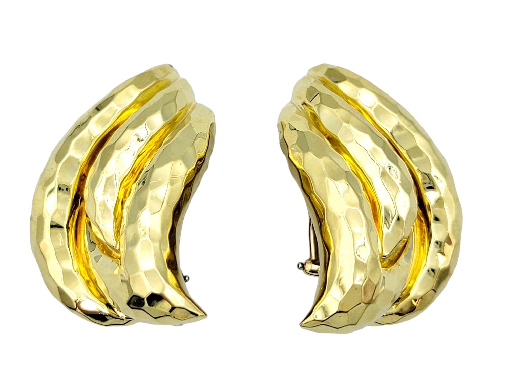 This gorgeous pair of Henry Dunay clip-on earrings, crafted in radiant 18 karat yellow gold, is a testament to the designer's distinctive artistry and craftsmanship. The large flame-like design, adorned with a hammered finish, creates a mesmerizing
