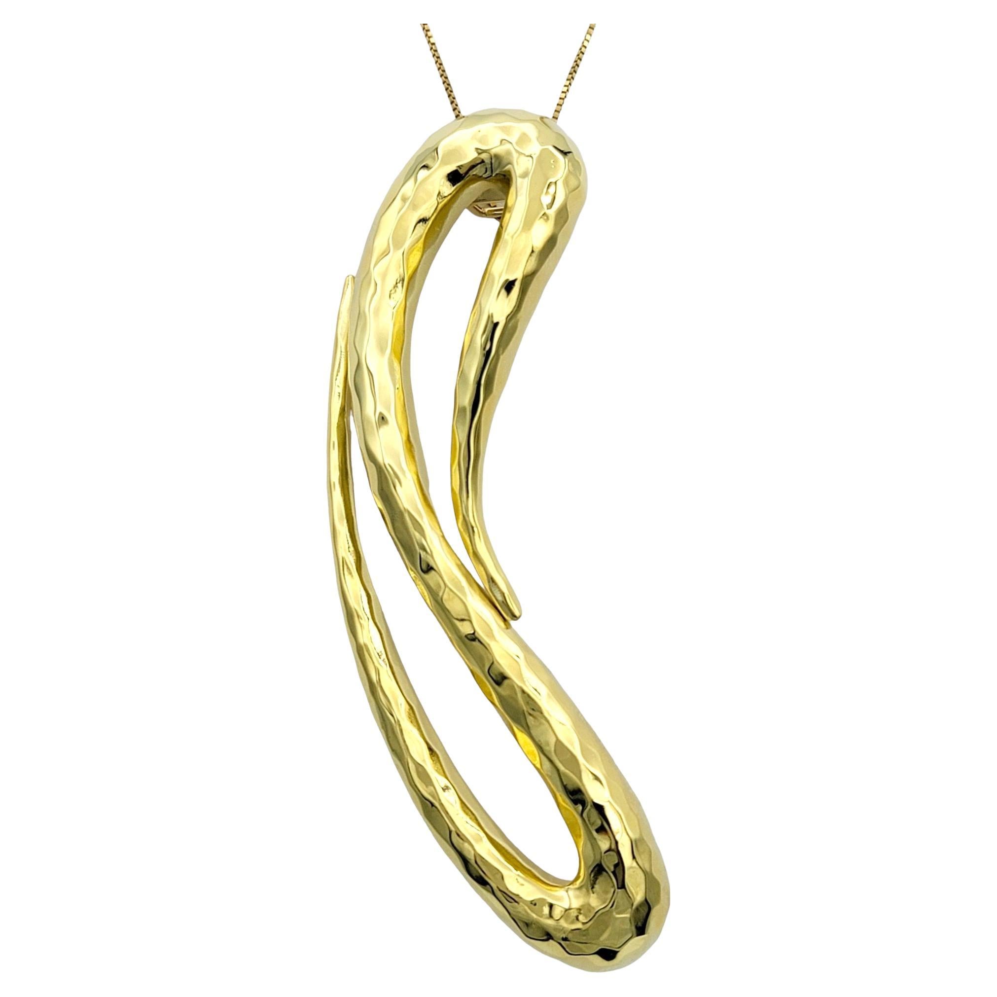 The Henry Dunay slider pendant is a masterful creation crafted in 18 karat yellow gold. Its distinctive smooth loop shape gives it a sense of fluidity and movement, while the hammered finish adds texture and depth to the piece.

This pendant