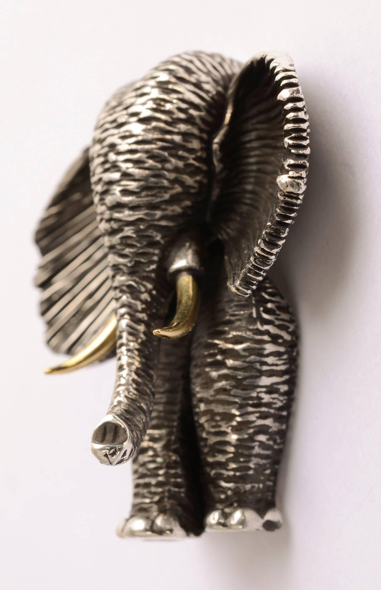 Wonderfully sculptural elephant brooch by American designer, Henry Dunay. The sterling silver body is well textured. The tusks are gold, perhaps to represent how precious they are. The brooch measures 1 3/4 inches in length and 1  5/8 inches from