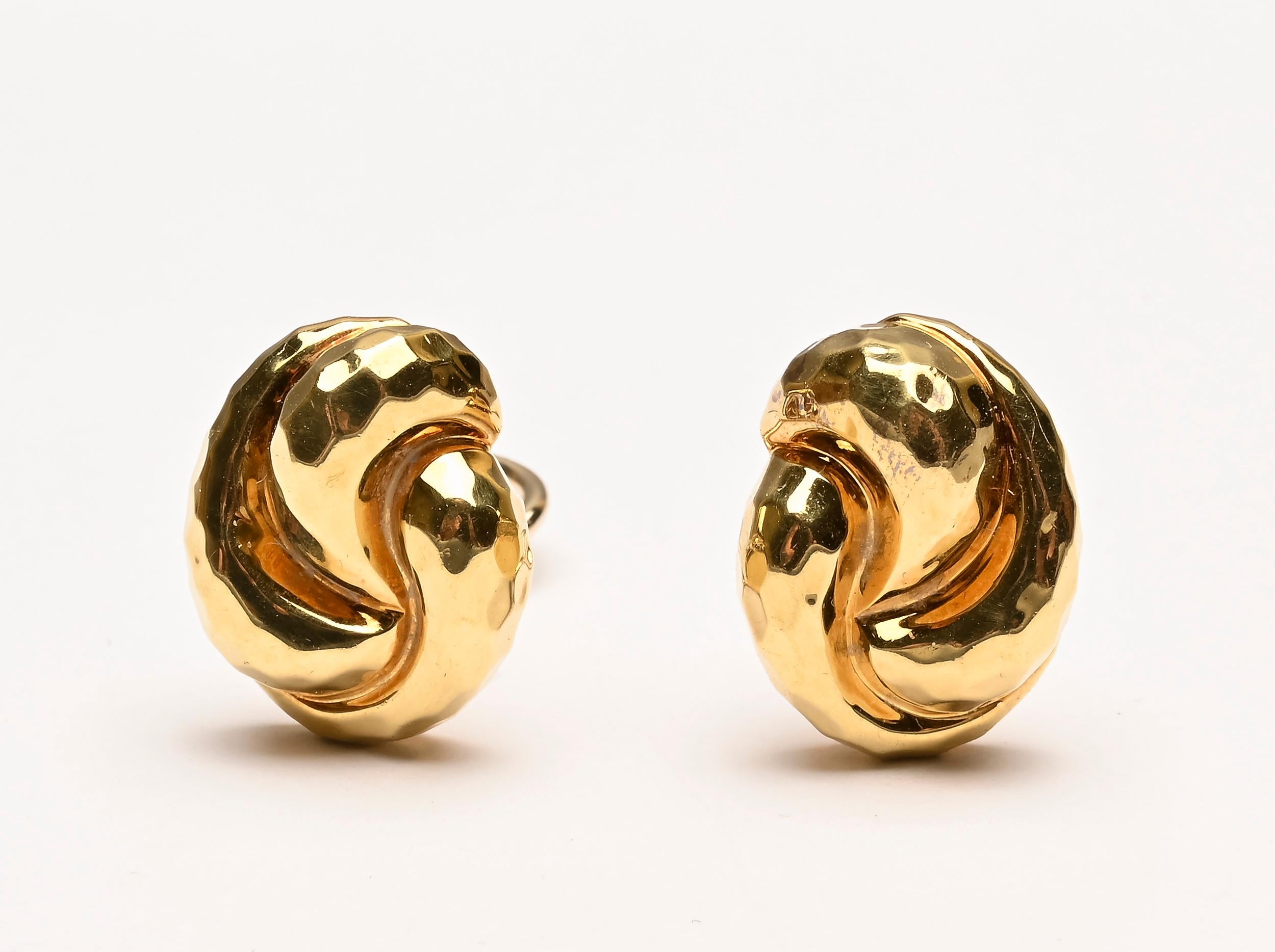 Henry Dunay 18 karat gold knot earrings that are typical of his design but smaller than his usual size. The earrings measure half an inch wide by 9/16 inch long. They are done with the hammered gold that is one of Dunay's signature finishes. Backs