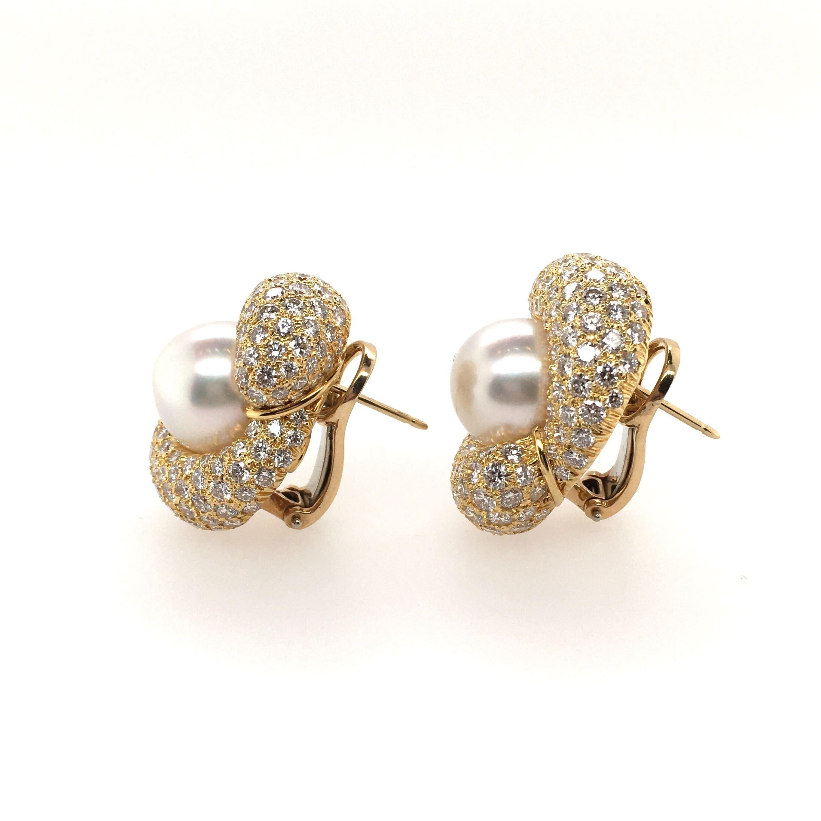A pair of 18 karat yellow gold, diamond and South Sea pearl earrings.  Henry Dunay.  Designed as a pave set diamond knot, centering a creamy white South Sea pearl measuring 12.7 mm.  Two hundred and forty diamonds weigh approximately 8.00 carats. 
