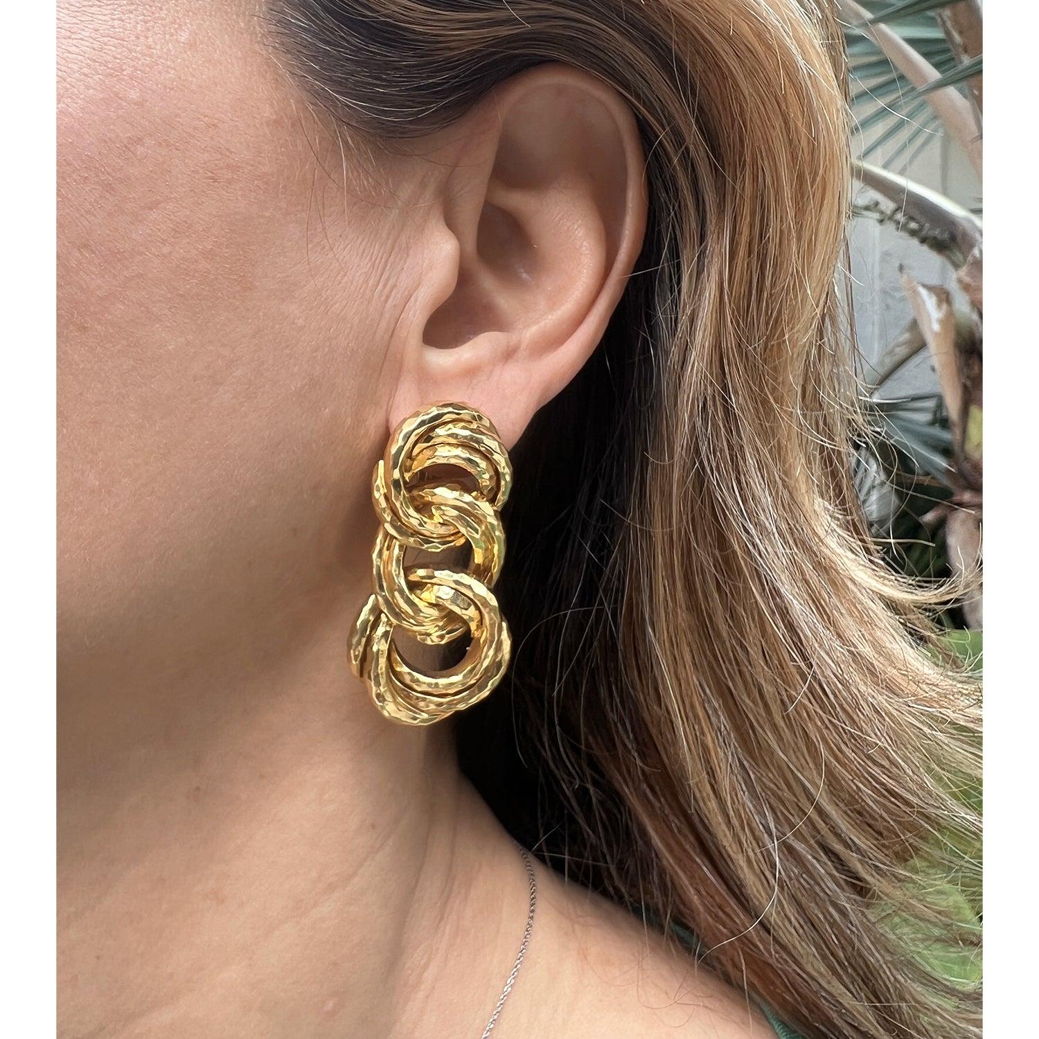 Henry Dunay 18k yellow gold earrings, each designed as three graduated hammered gold interlocking triple circle links.  Stamped with maker's mark for Henry Dunay, 