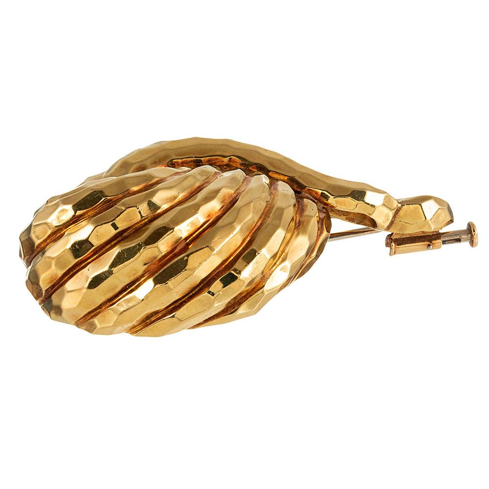 Substantial and sophisticated, this textured golden brooch is designed as a series of sweeping golden strokes hat form a loose knot. Made of 18 karat yellow gold and signed Henry Dunay. 2 inches by 1.25 inches.