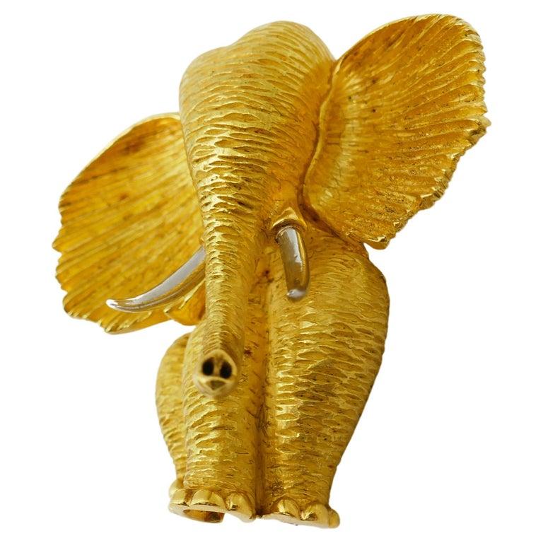 A cute elephant brooch by Henry Dunay. Made of 18k yellow gold. Tusks are platinum. Stamped with  Henry Dunay maker's mark, a serial number and the hallmarks for 18k gold and 5% ruthenium platinum. 
Measurements: 1 3/4