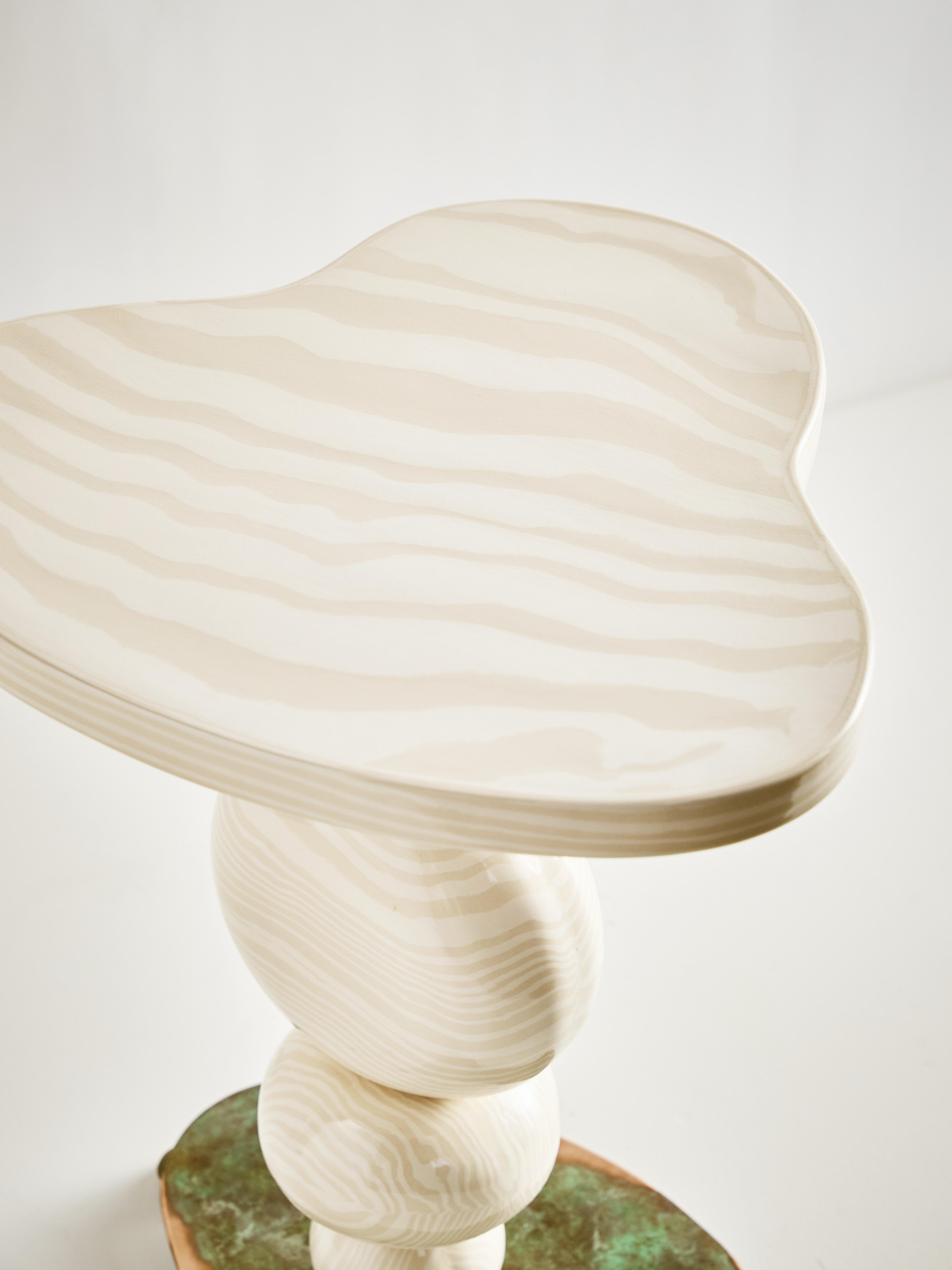 La table d'appoint Alto rehausse votre espace, aussi petit soit-il. Fabriqué à la main selon les techniques traditionnelles de construction de dalles Nerikomi. Des sphères en céramique sont enfilées sur une colonne centrale, reposant sous une