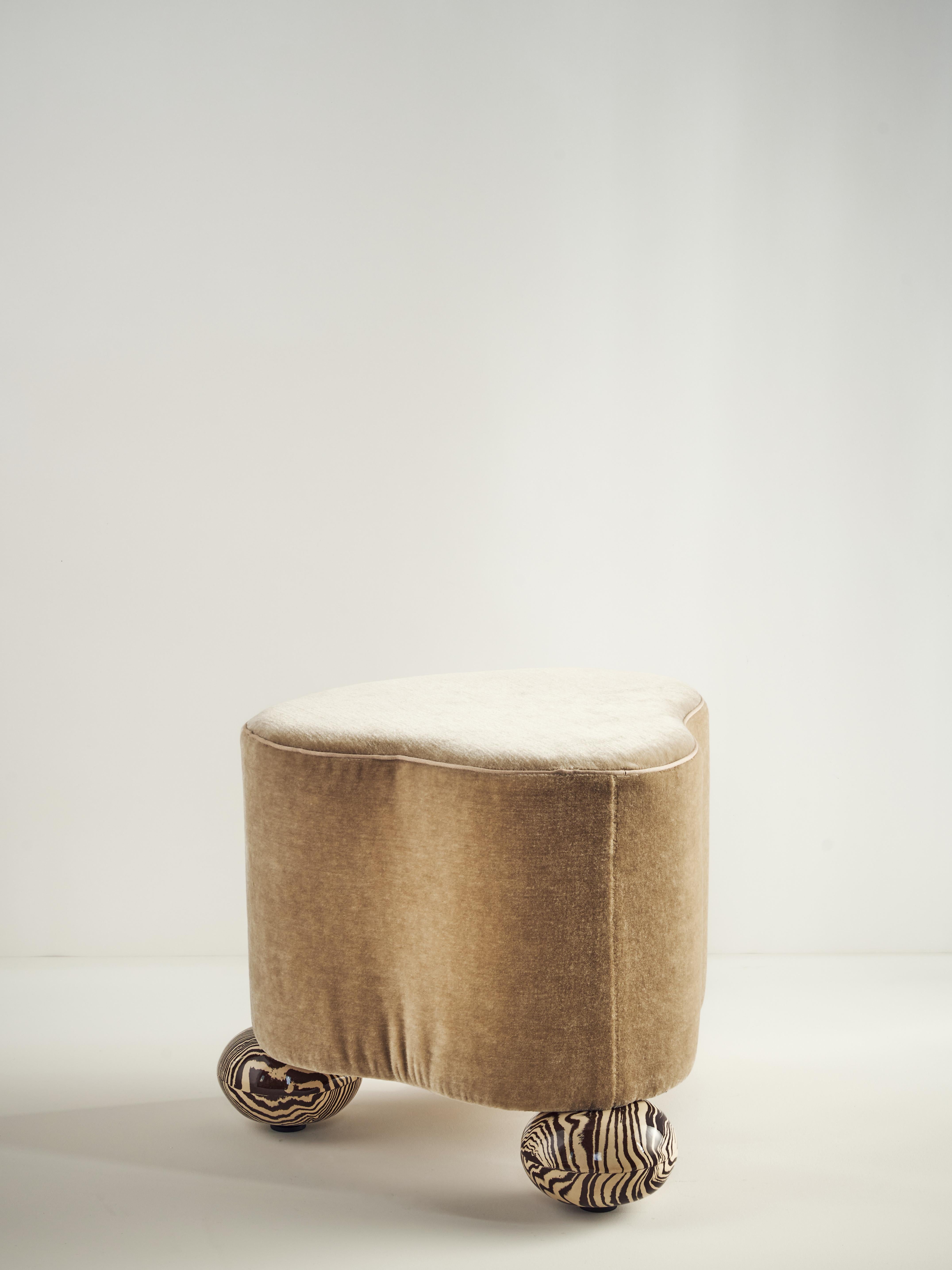 Le pouf 'Cirrus' est la plus petite pièce de notre collection de meubles, mais il le compense par son caractère. Une forme organique rembourrée, semblable à un nuage, repose sur 3 sphères en céramique fabriquées à la main par Nerikomi dans notre