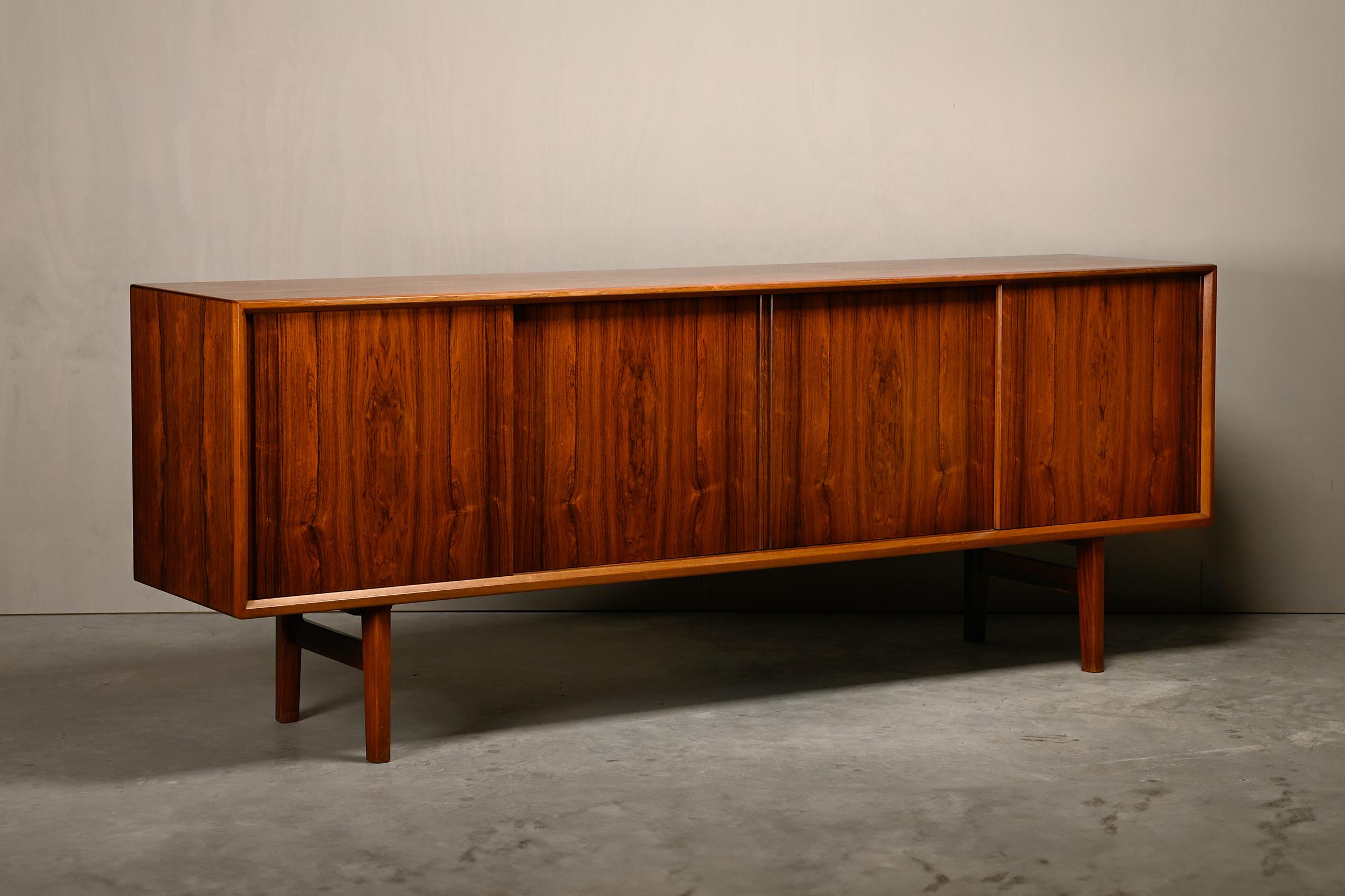 Beautiful large rosewood sideboard designed by Henry Kjærnulf for Bruno Hansen, Denmark, 1960s. The sideboard is divided into 4 sections accessible via sliding doors, three of which have adjustable shelves and a section with five drawers. The