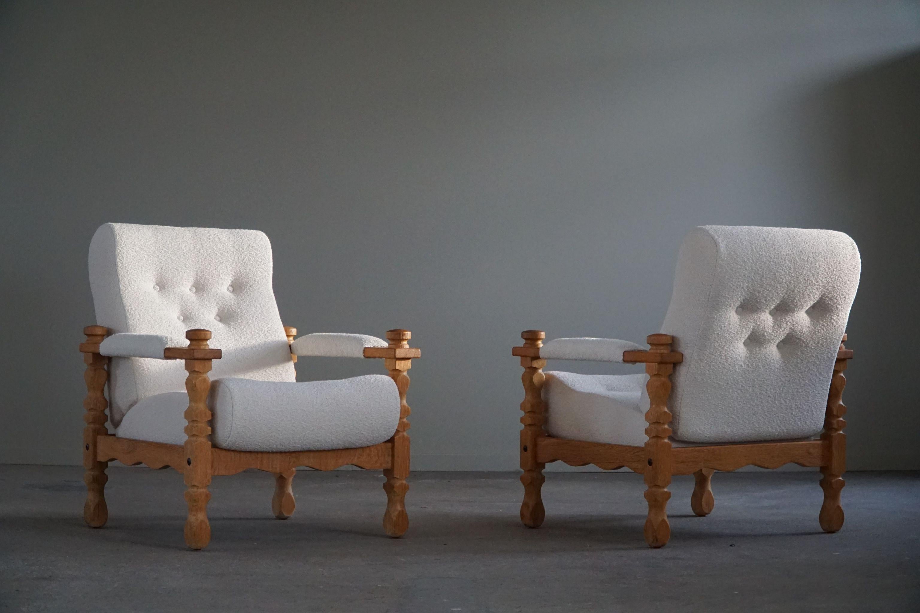Such an intriguing sculptural pair of Danish modern lounge chairs in the style of Henning (Henry) Kjærnulf. Made in oak and reupholstered in a fine eggshell bouclé wool. Made in 1960s by a Danish Cabinetmaker with a great sense for details. The