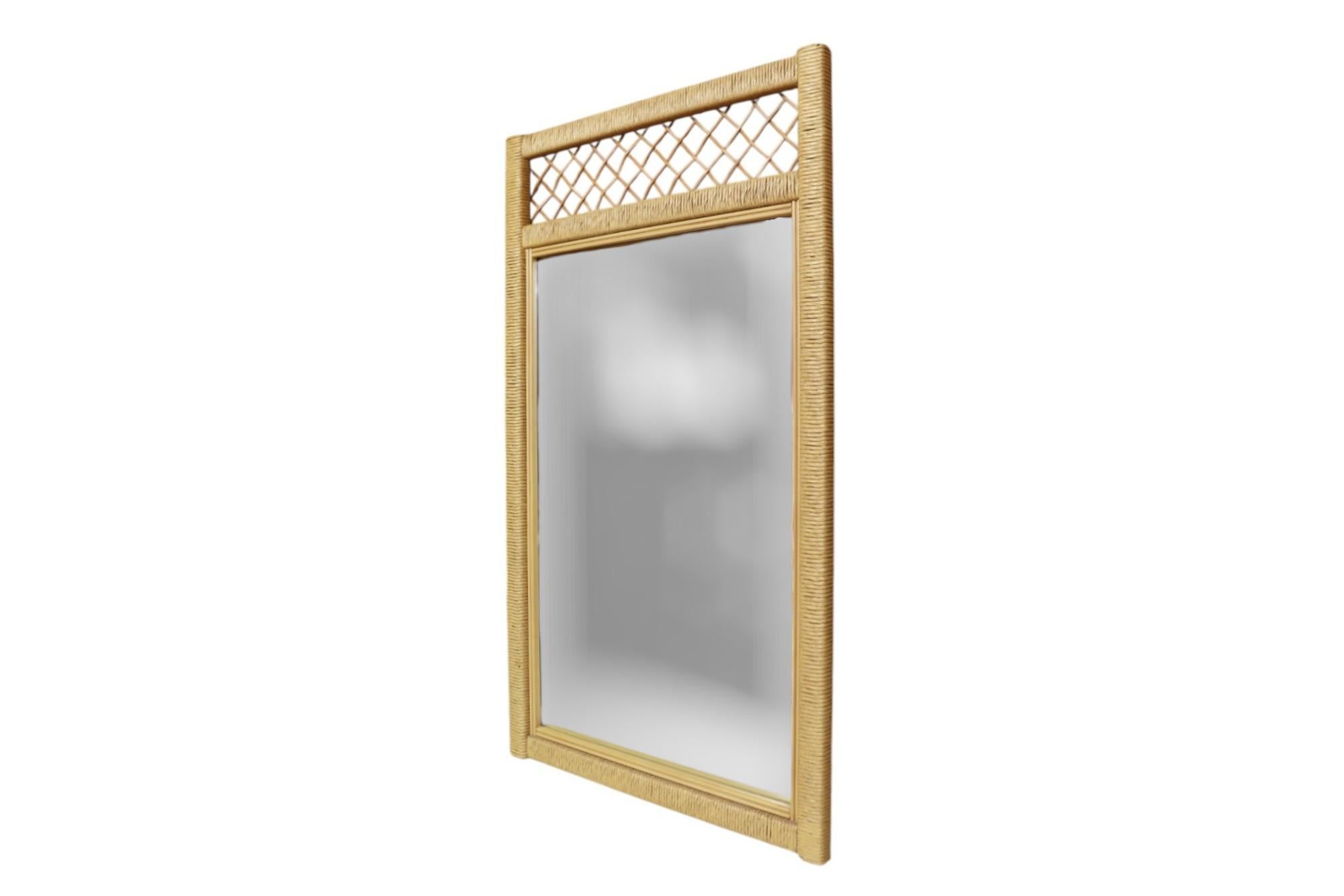 A vertical Henry Link for Lexington wall mirror. The wooden frame is wrapped with rattan, surmounted with a pencil bamboo latticed trellis. Manufacturer's mark is visible in the back.