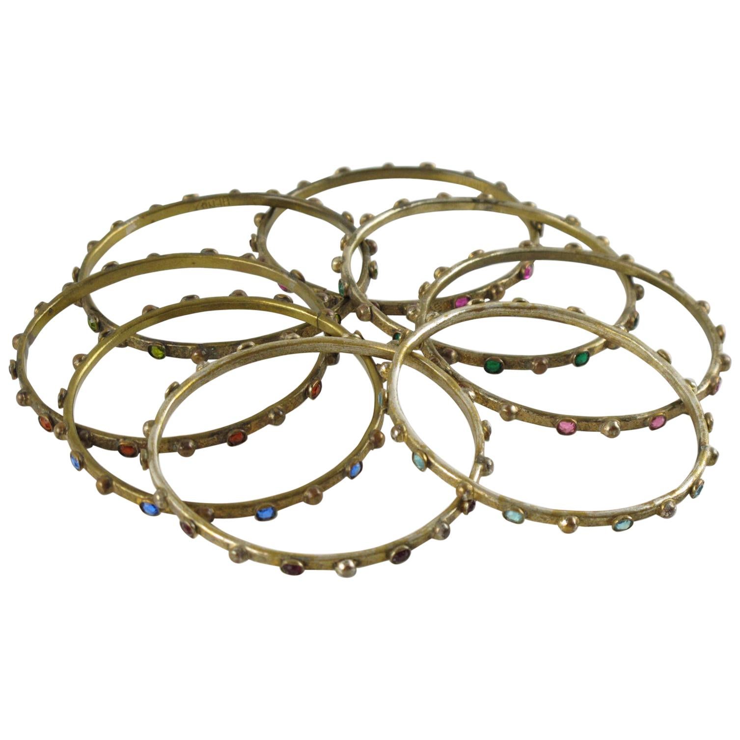 Il designer francese di gioielli Henry Perichon ha creato questo splendido insieme di otto braccialetti distanziatori in bronzo dorato. Il set presenta un design di ispirazione rinascimentale, ornato da strass di cristallo nei colori rosso rubino,
