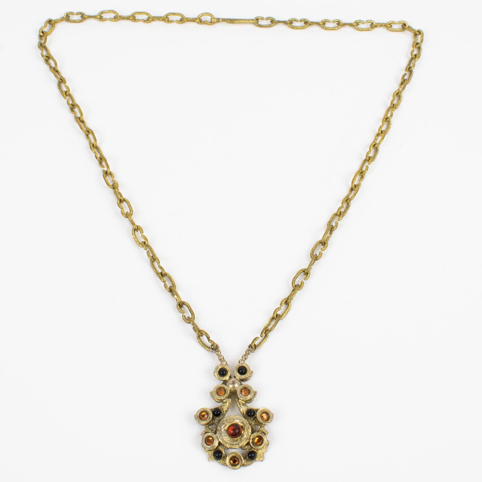 Henry Perichon (aka Henry) designed this elegant Medieval revival gilded bronze pendant necklace in the 1950s. The bronze metal pendant has an antique Middle-Age design influence and is ornate with black and paprika red poured glass cabochons and