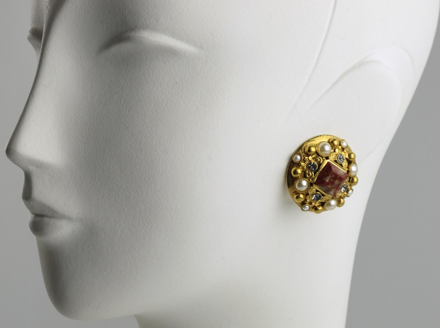 French Jewelry designer Henry Perichon (aka Henry) designed these lovely clip-on earrings in the 1960s. The rounded gilt metal shape is inspired by Baroque and Medieval design and is ornate with pearl-like, square agate-like gemstones and