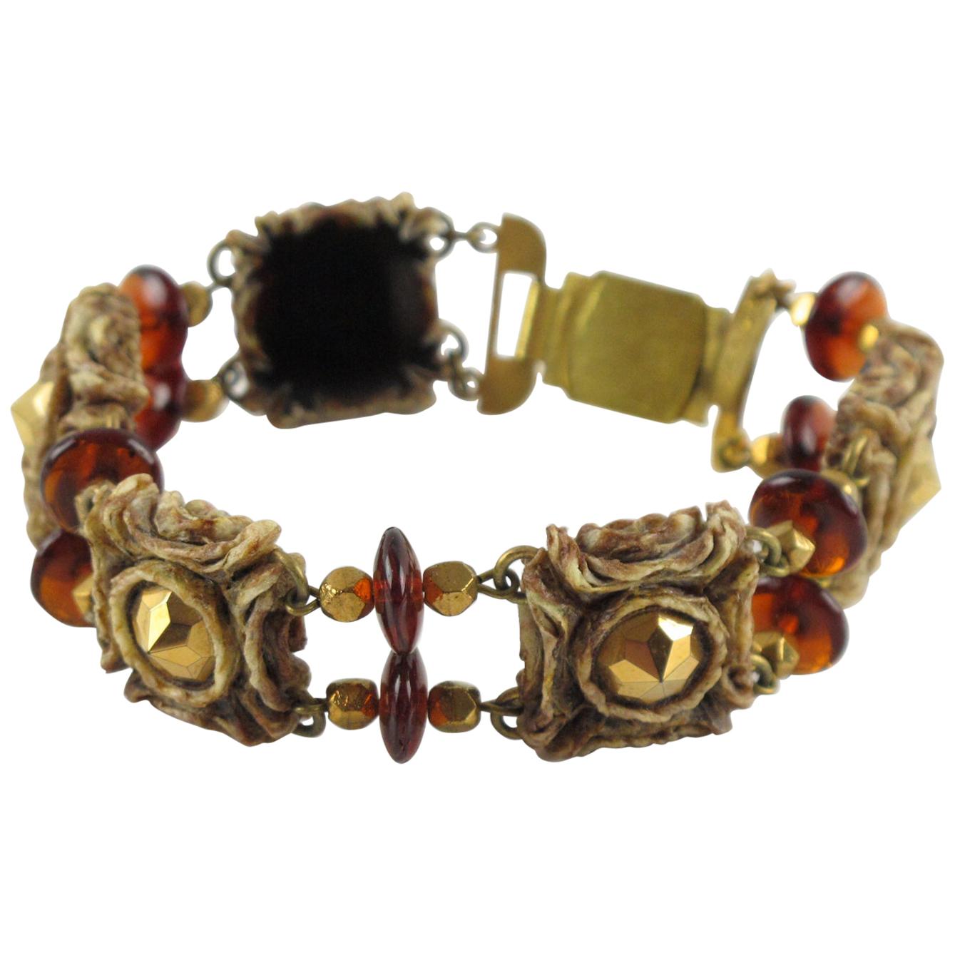 Henry Perichon, diseñador de joyas francés, creó esta impresionante pulsera de eslabones de resina adornada con cuentas de cristal color ámbar y piedras metálicas. An He revolucionó la industria de la joyería de plástico con su invento del