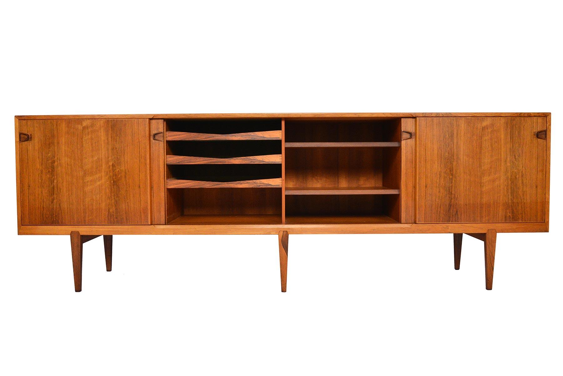 This gorgeous credenza was designed by Henry Rosengren Hansen for Brande Møbelindustri in 1950. Minimalist details and expert craftsmanship showcase dramatic bookmatched Brazilian rosewood grain. Four sliding doors open to four bays outfitted with