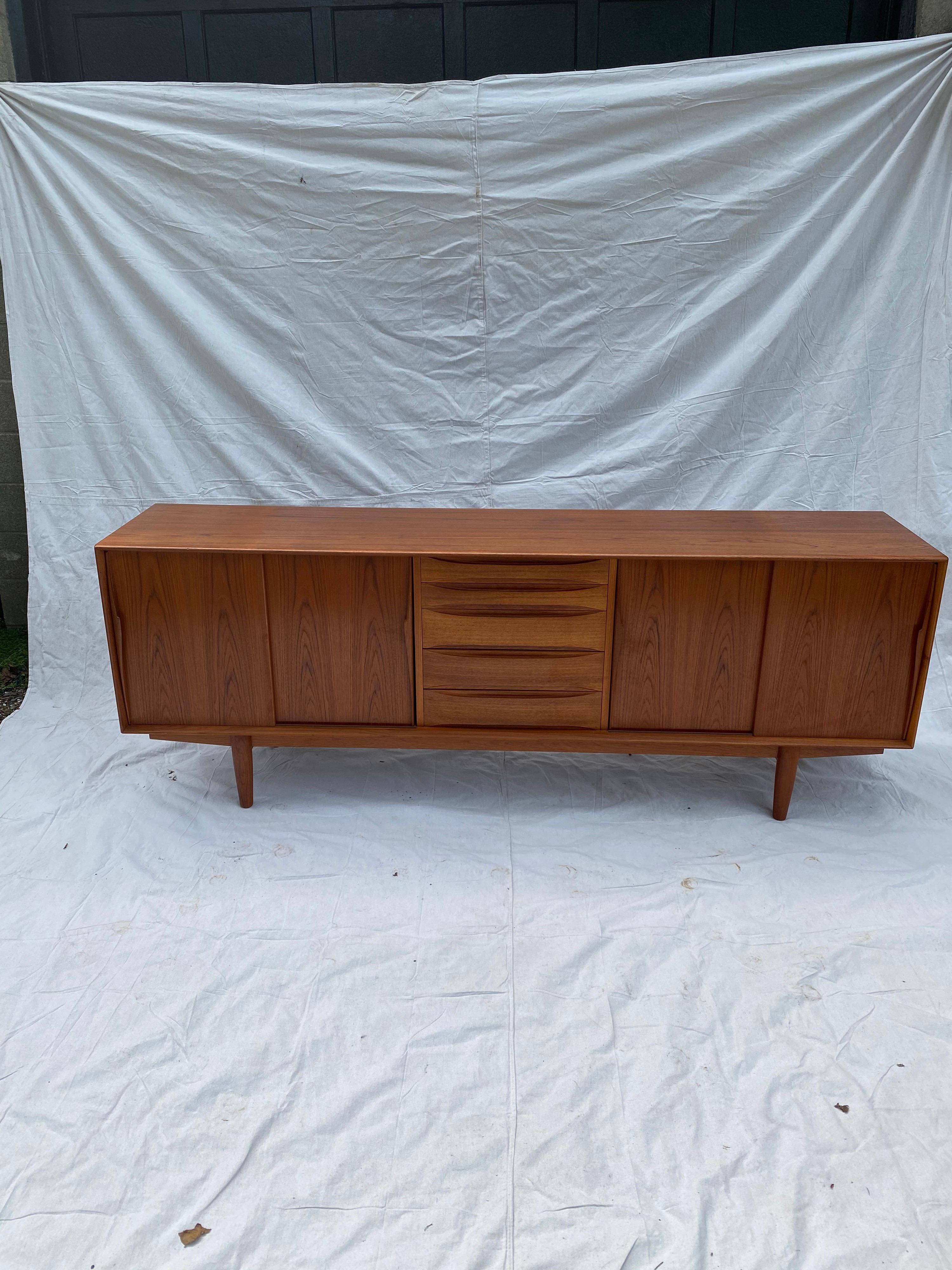 Henry Rosengren Hansen teak credenza or buffet. Beautiful design with tons of storage! 5 center drawers and 4 sliding doors open to reveal adjustable shelf’s. Original finish is very nice, top shows 2 very slight shadow marks.
