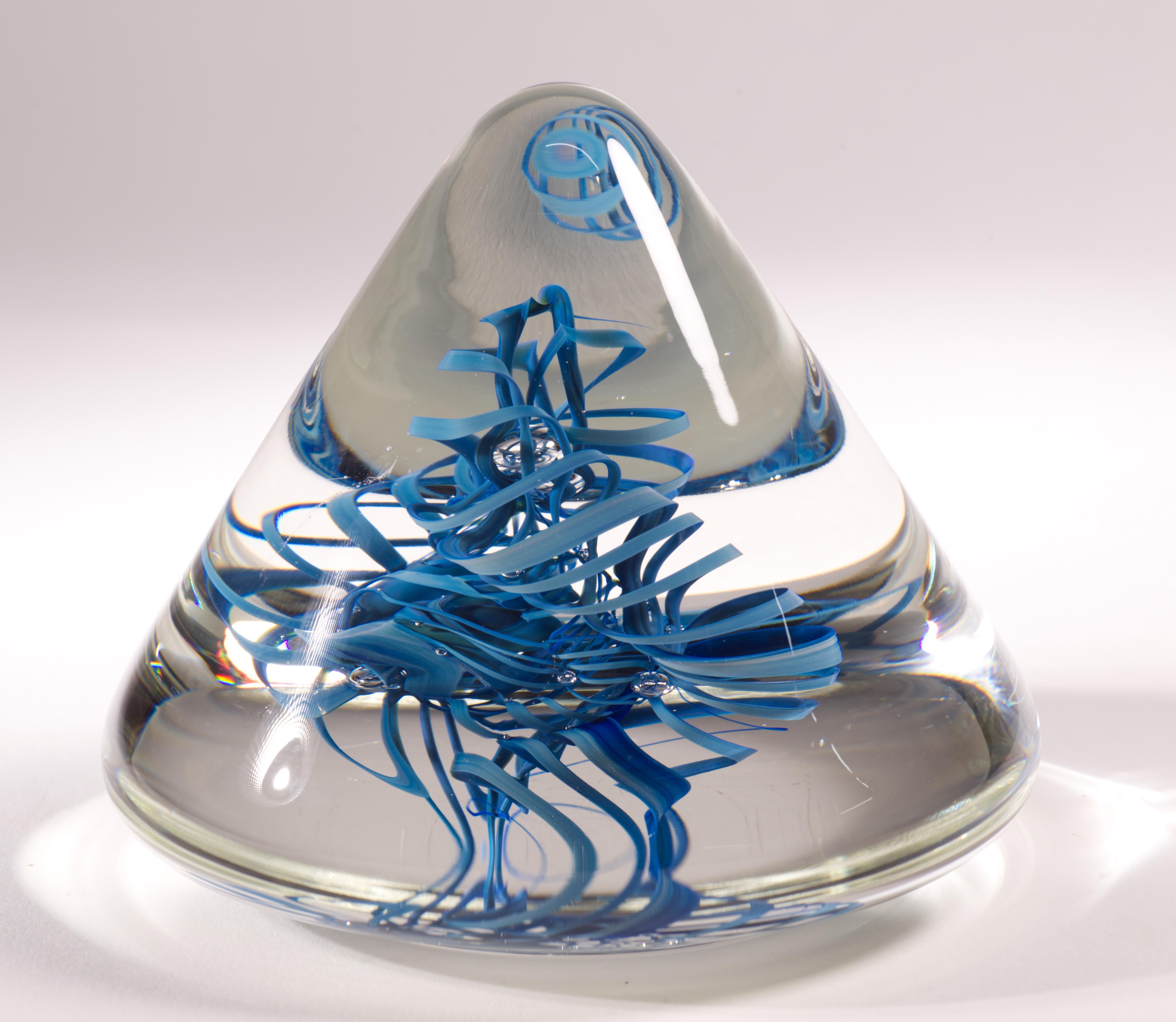  La scultura grafica in vetro o fermacarte è stata creata con spirali elicoidali di vetro blu intrecciate e un nucleo di bolle controllate fuse in uno strato di vetro trasparente con la tecnica del sommerso. La scultura ha una forma triangolare con