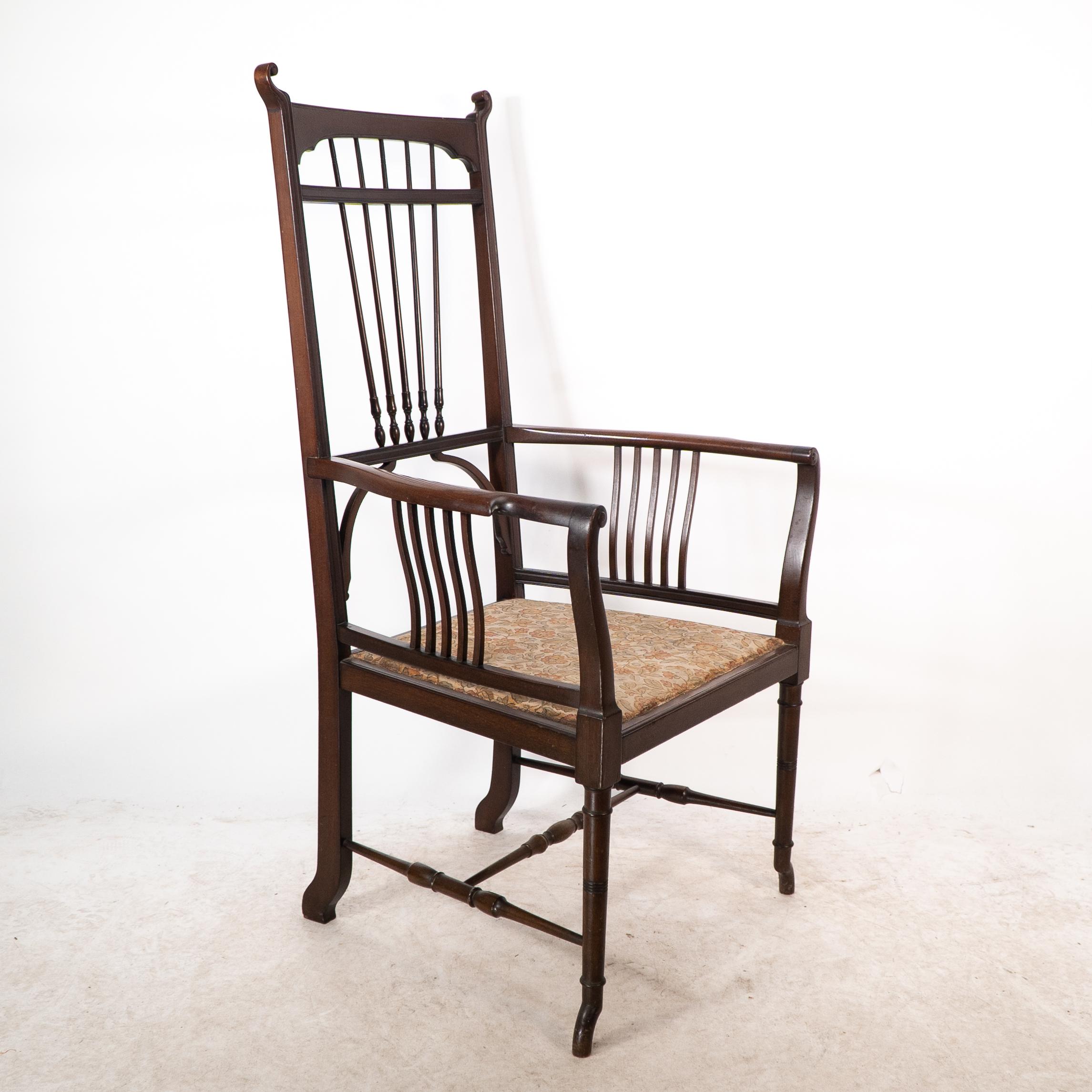 Atribuido a Henry Batley. Sillón de nogal del Aesthetic Movement con toques sinuosos, remates rizados y un rocío de detalles torneados alargados en el respaldo. Los brazos perfilados tienen debajo unos soportes curvilíneos que unen el asiento, con
