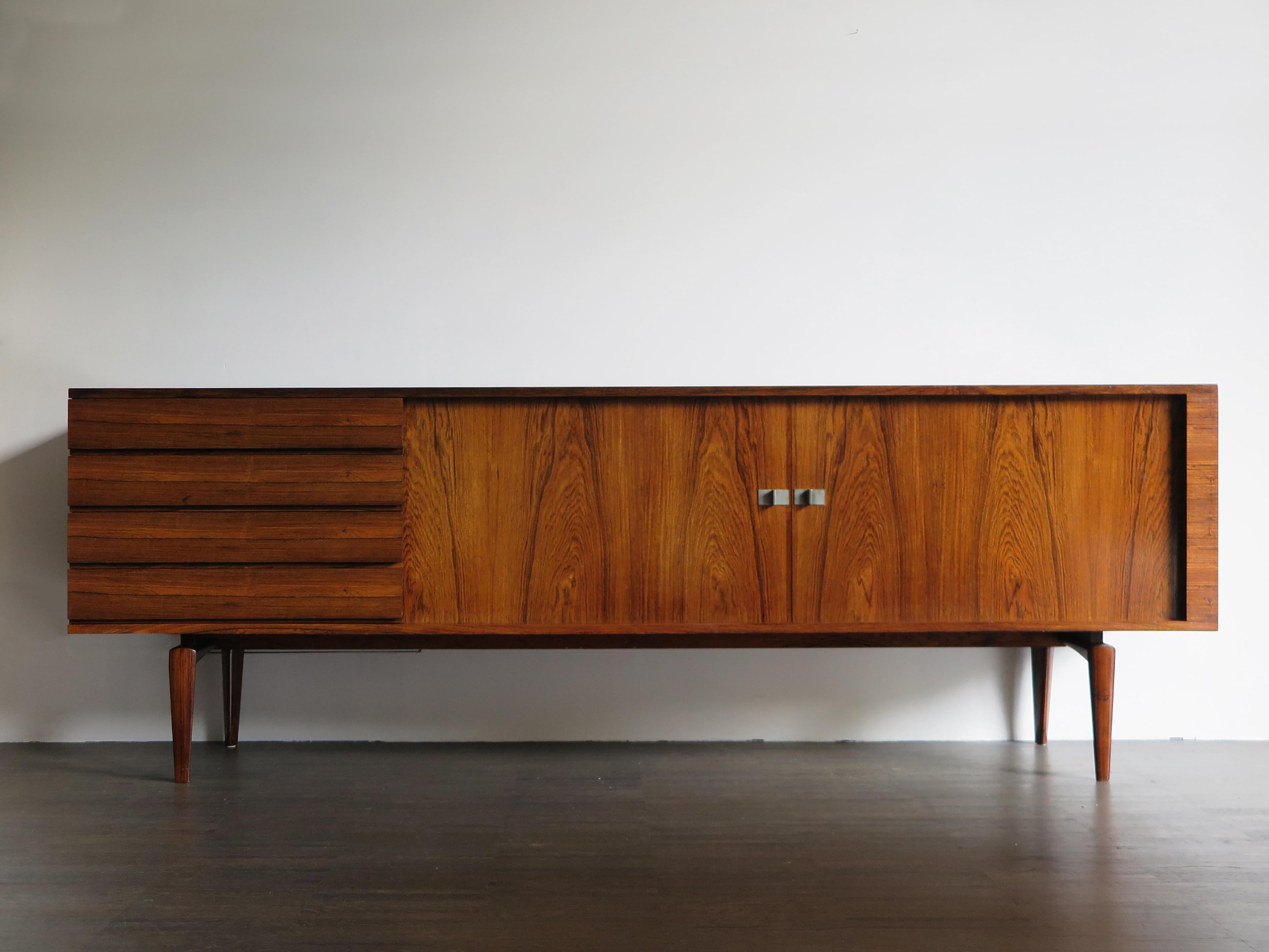 Scandinavian Mid-Century Modern design dark wood sideboard designed by Henry Walther Klein and produced by Bramin Mobelfabrik with two sliding doors and four chest of drawers, Denmark 1950s.

Please note that the sideboard is original of the