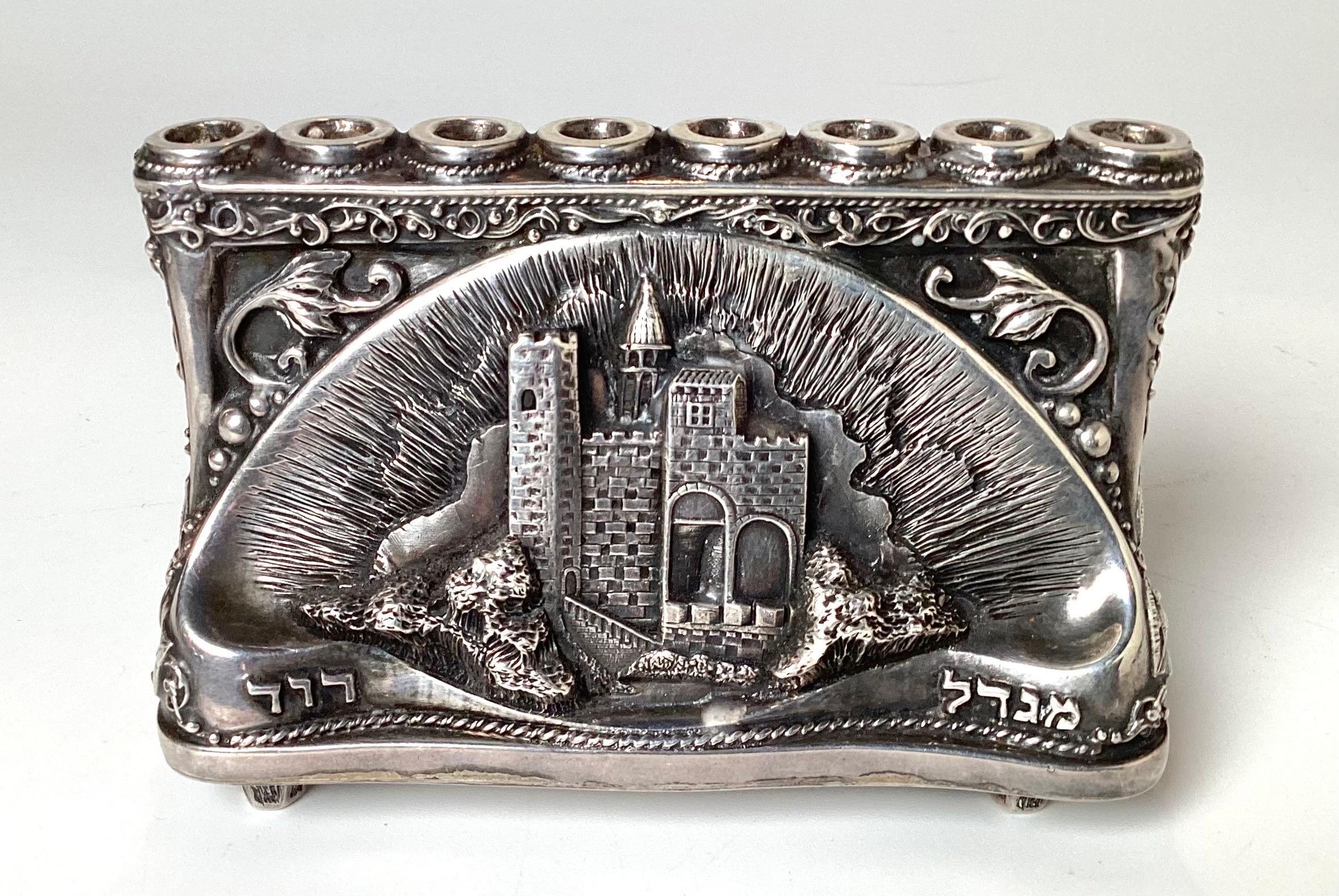A signed Henryk Winograd 99.9 Silver diminutive menorah. Hand made repose with high relief details. 3 icnes high, 4 inches wide, 2 inches deep. 
Henryk Winograd was one of the world's greatest 20th century masters of traditional silversmithing