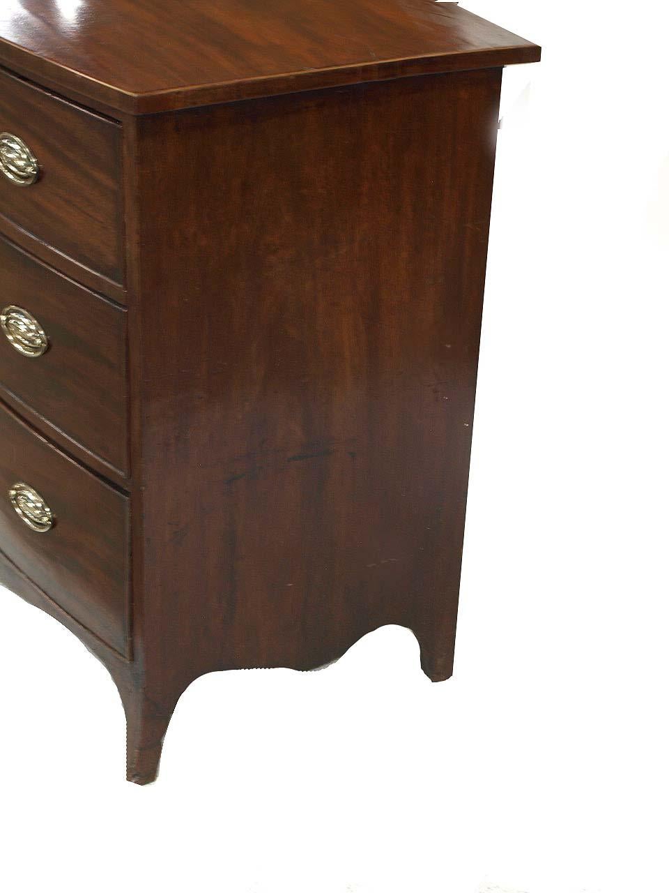 Hepplewhite bow front chest, the top of this mahogany chest has beautiful figured grain and the edge is banded with boxwood string inlay. The three graduated drawers have antique oval brass pulls, however, they are not original ; the chest has a