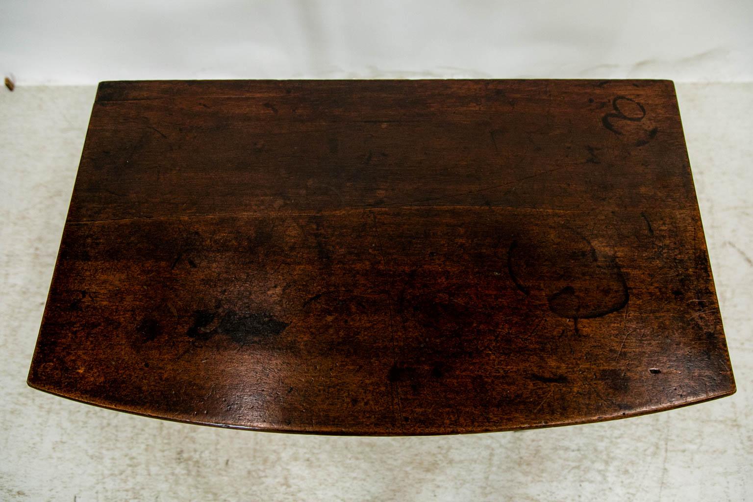 The drawer front of this side table has incised cockbead. The bowfront top has a bullnosed front and side edge. There is a 1/16 inch shrinkage separation in the top which has some marks and staining commensurate with age and use.
 