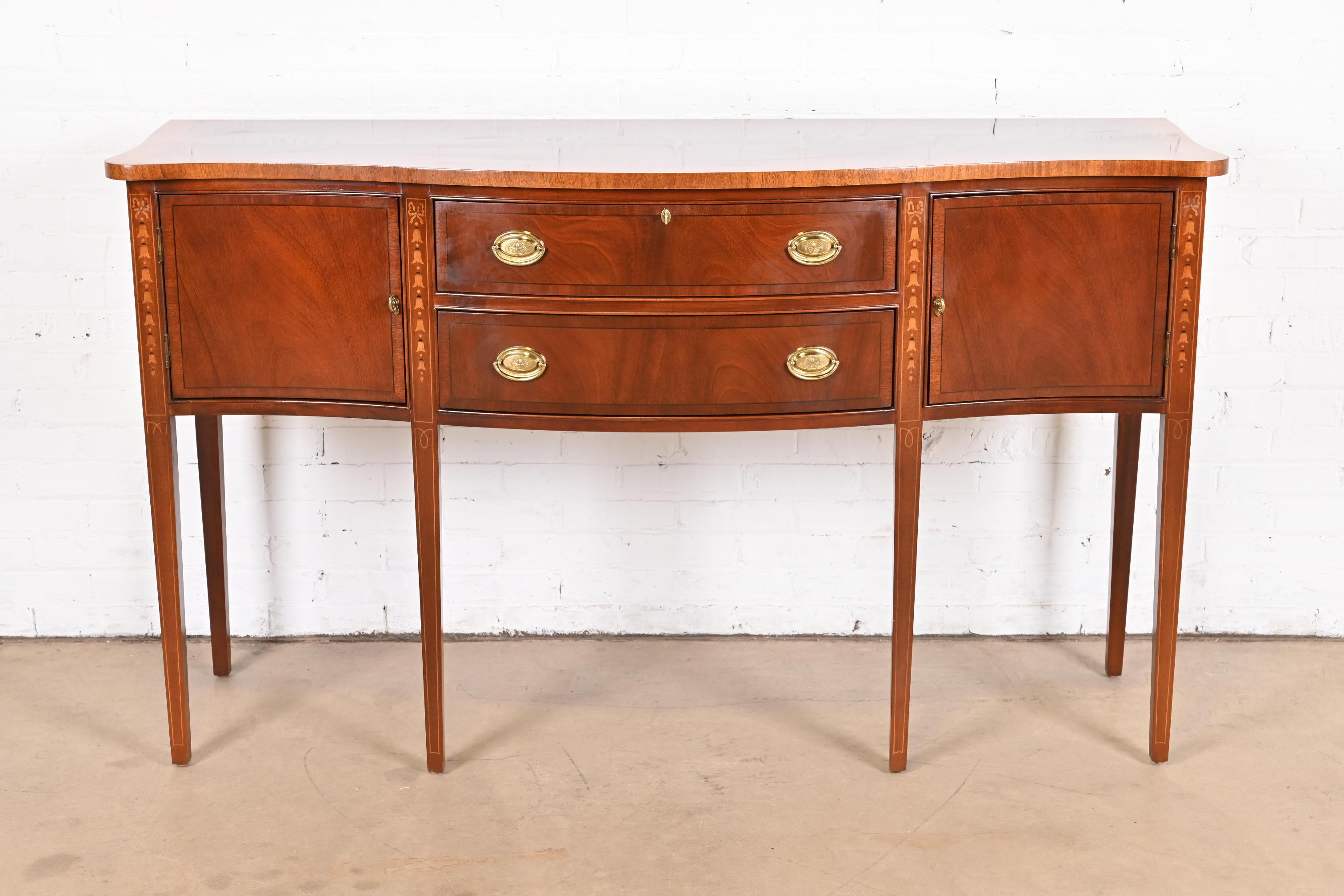 A gorgeous Hepplewhite or Federal style serpentine front sideboard, buffet, or credenza

USA, Late 20th Century

Flame mahogany, with inlaid satinwood marquetry and banding, and original brass hardware. Top drawer locks, and key is
