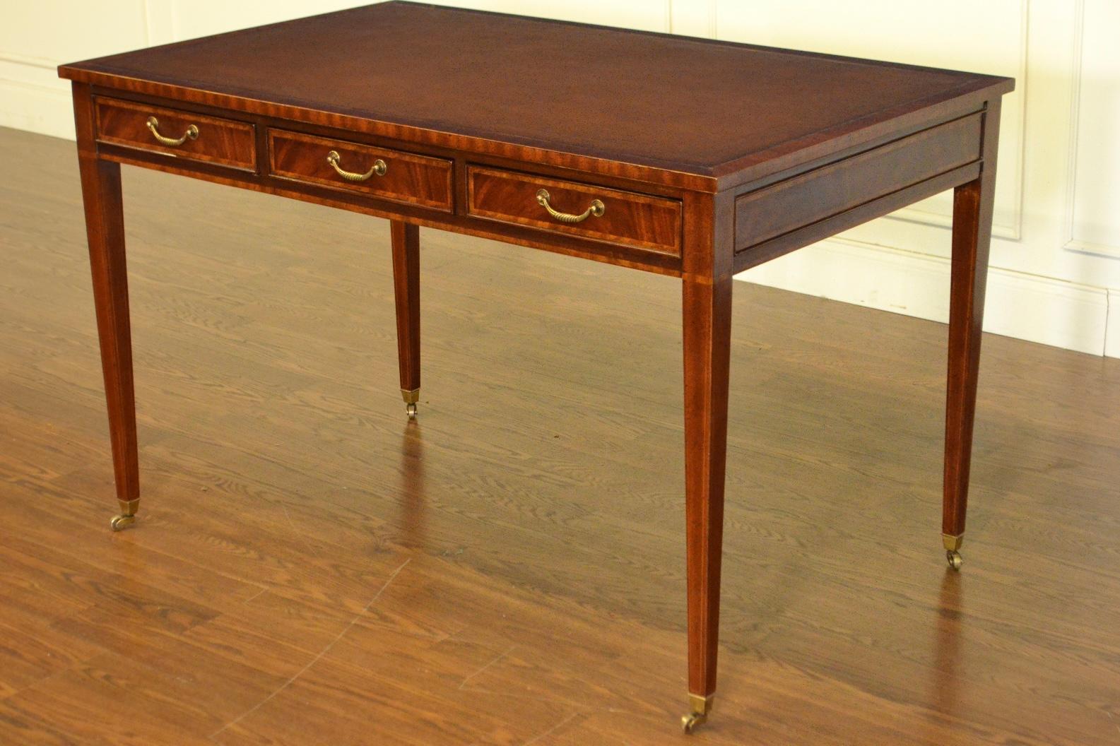 This is a new Hepplewhite style writing desk. It is ideal for the home office, library, or reception area in a business setting. It features a top of brown leather with gold tooling. Its front, back and side panels and drawers have crotch mahogany