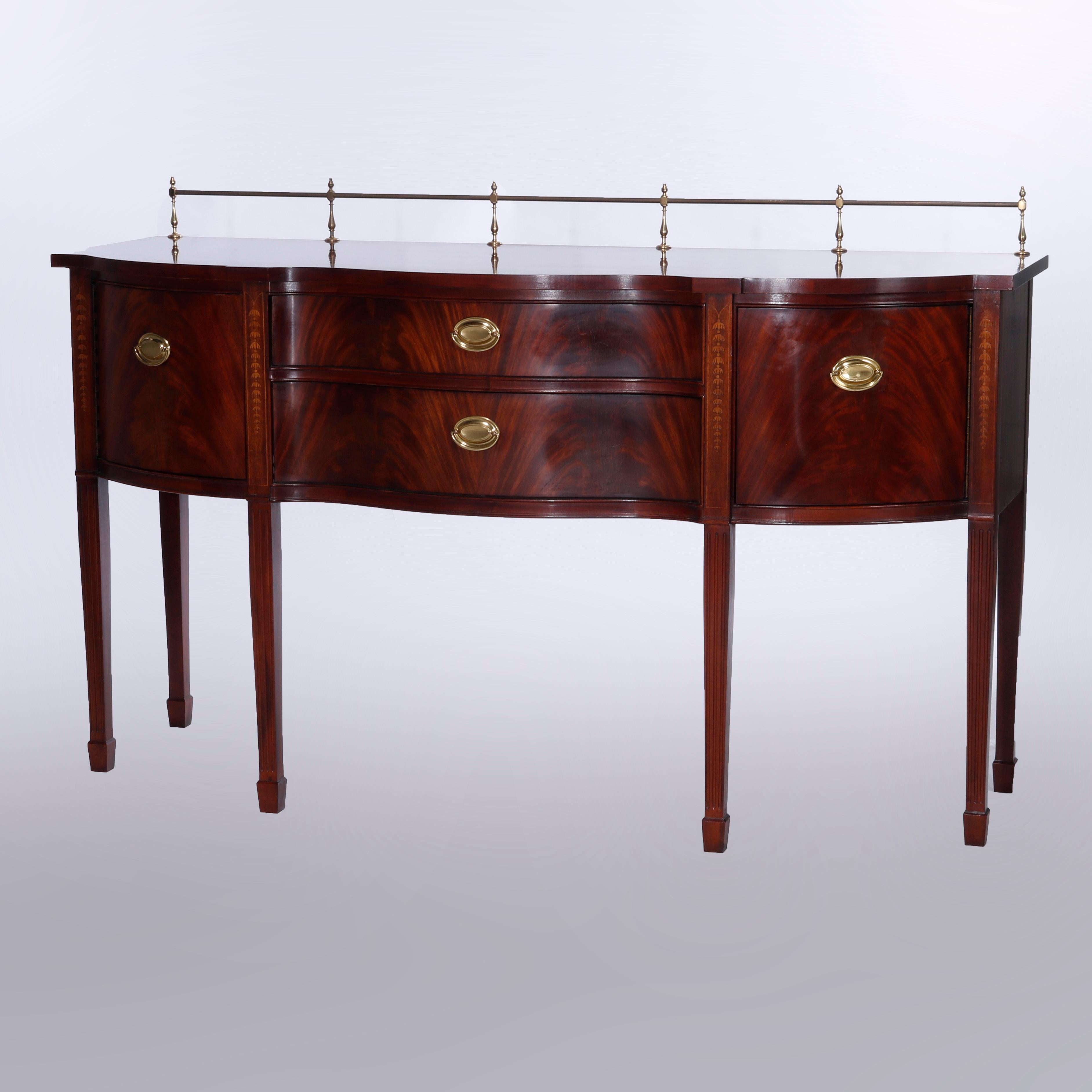 A Hepplewhite style sideboard by Thomasville offers flame mahogany construction in serpentine form with top having brass rail over case with central double drawer stack and flanking blind cabinets, raised on tapered legs terminating in spade feet,