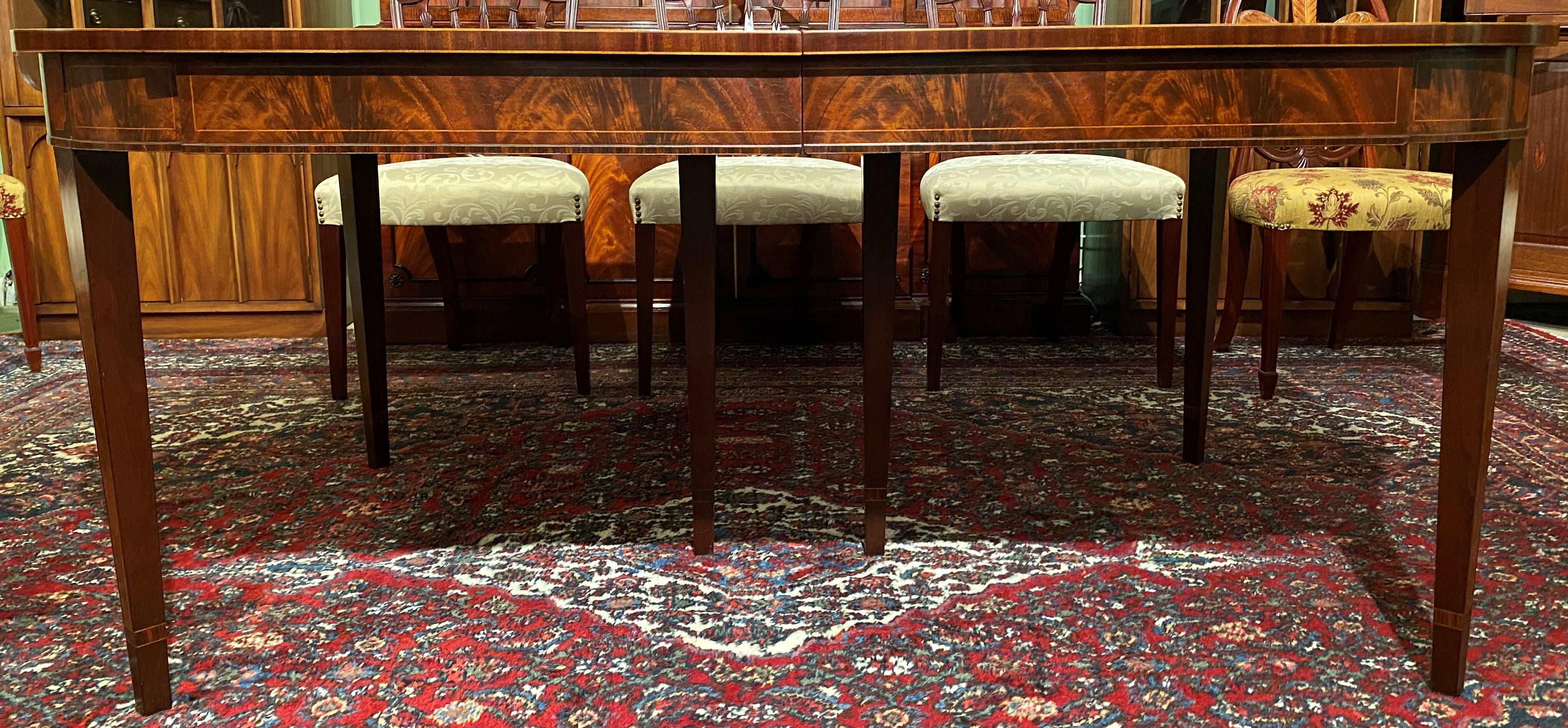 An exceptional custom mahogany dining table by Schmieg & Kotzian with tulip wood & burled elm inlay, as well as a rosewood table edge and banding on the tapered legs. A rectangular figured mahogany top with a high polish has astragal corners, a