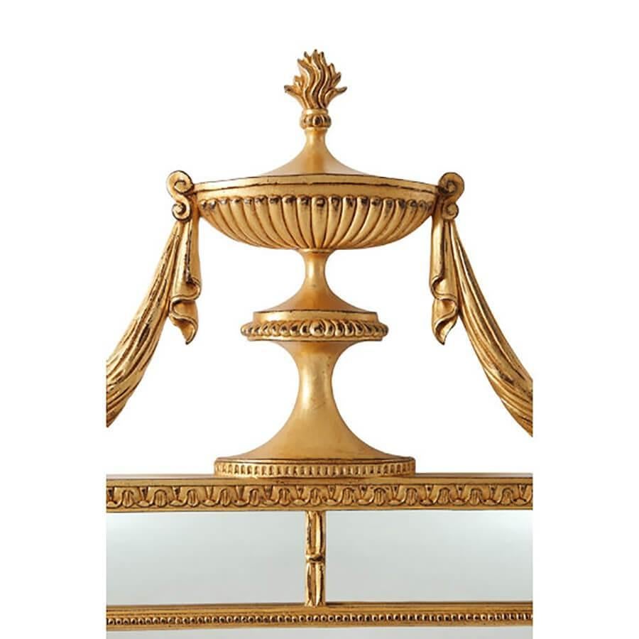 A George III (Hepplewhite) style gilt mirror with hand gold leaf, a bold reeded urn finial with swag drapery, with leaf details and a beaded frame.

Dimensions: 34.5
