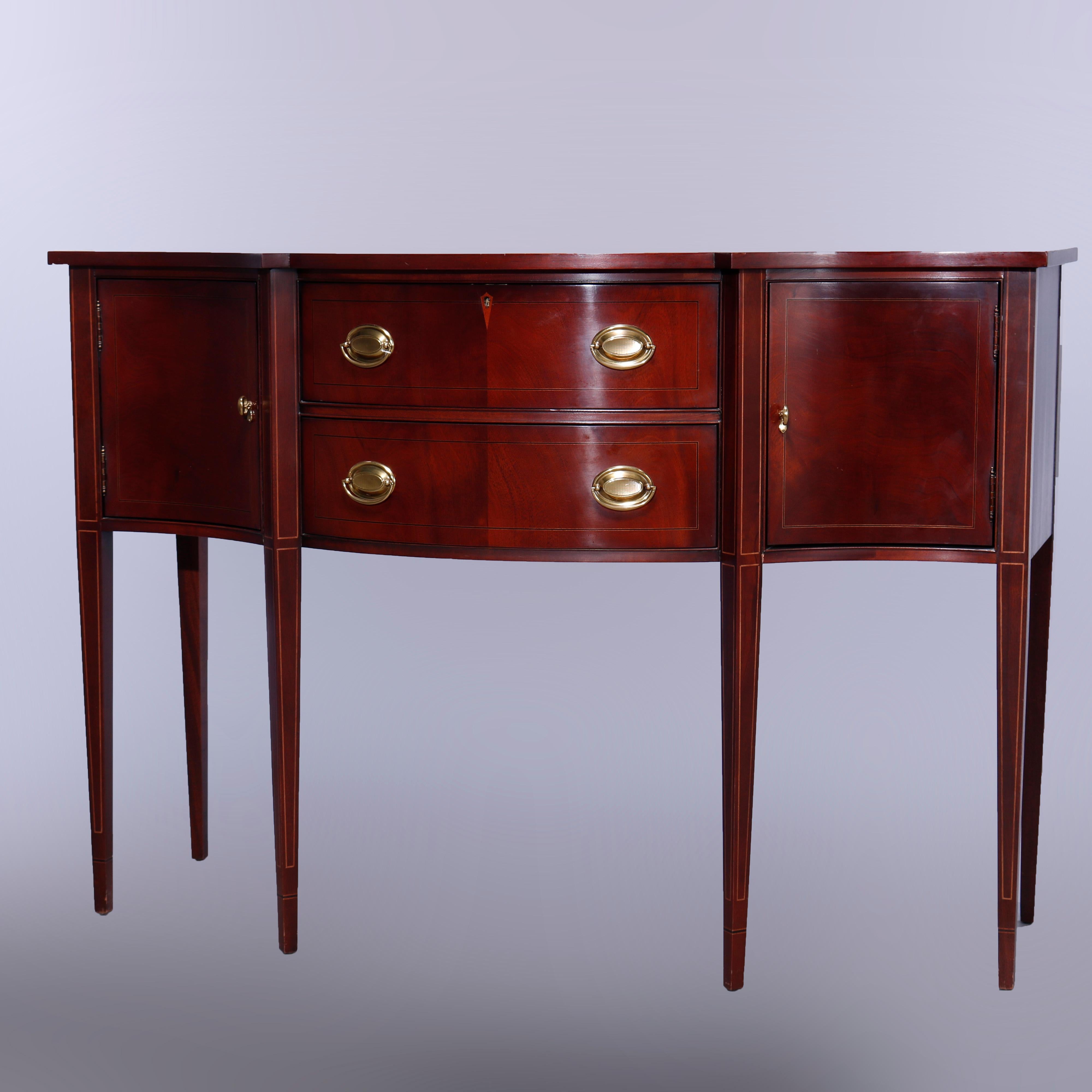 A silver server sideboard by Hickory Chair Co. offers mahogany construction in bow front form having shaped top over central convex drawer tower with flanking cabinets having curved concave doors, raised on tapered square legs, satinwood inlaid
