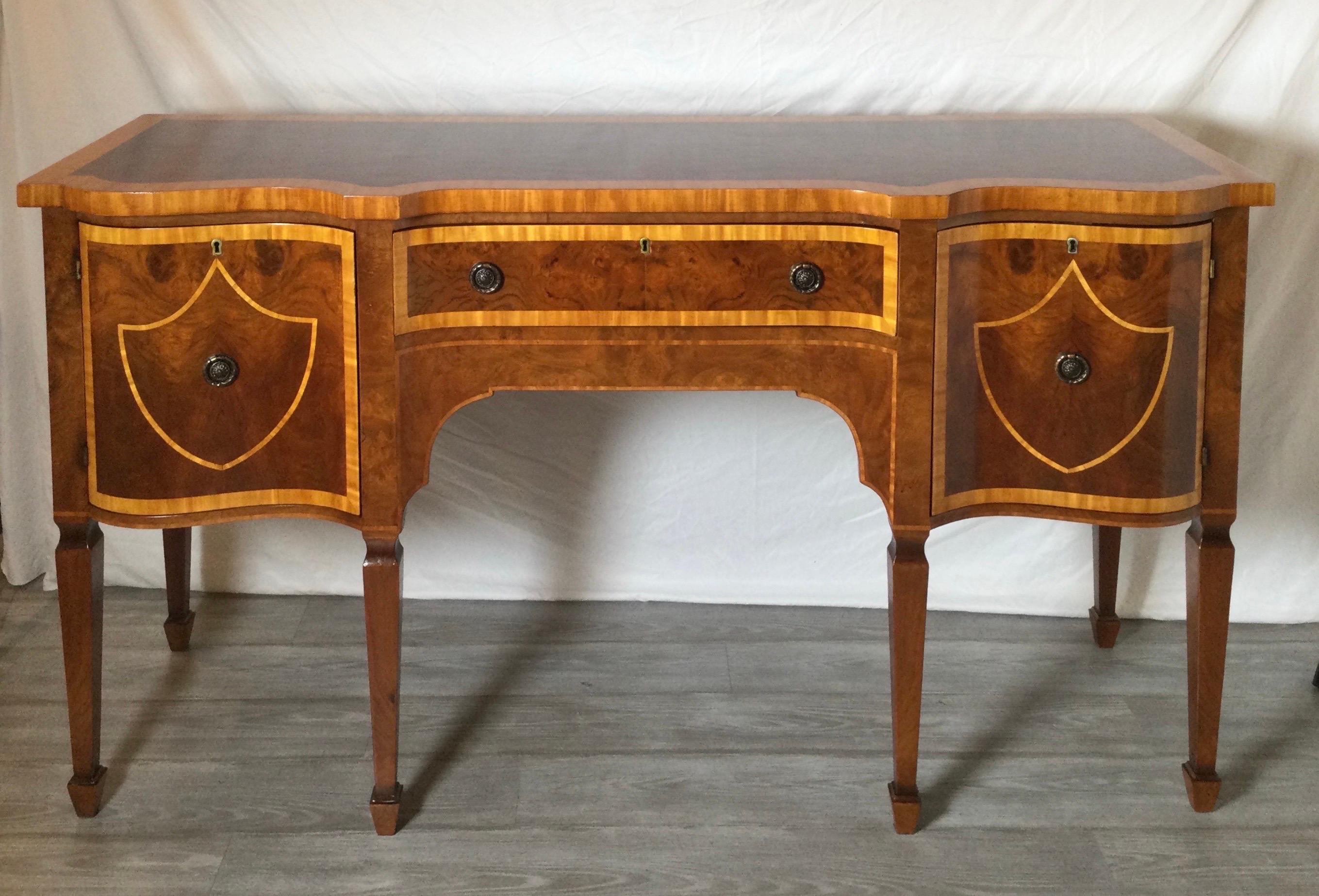 Elegant flame mahogany Hepplewhite style sideboard with satinwood cross banding. The sideboard with center drawer flanked by doors on each side with storage.