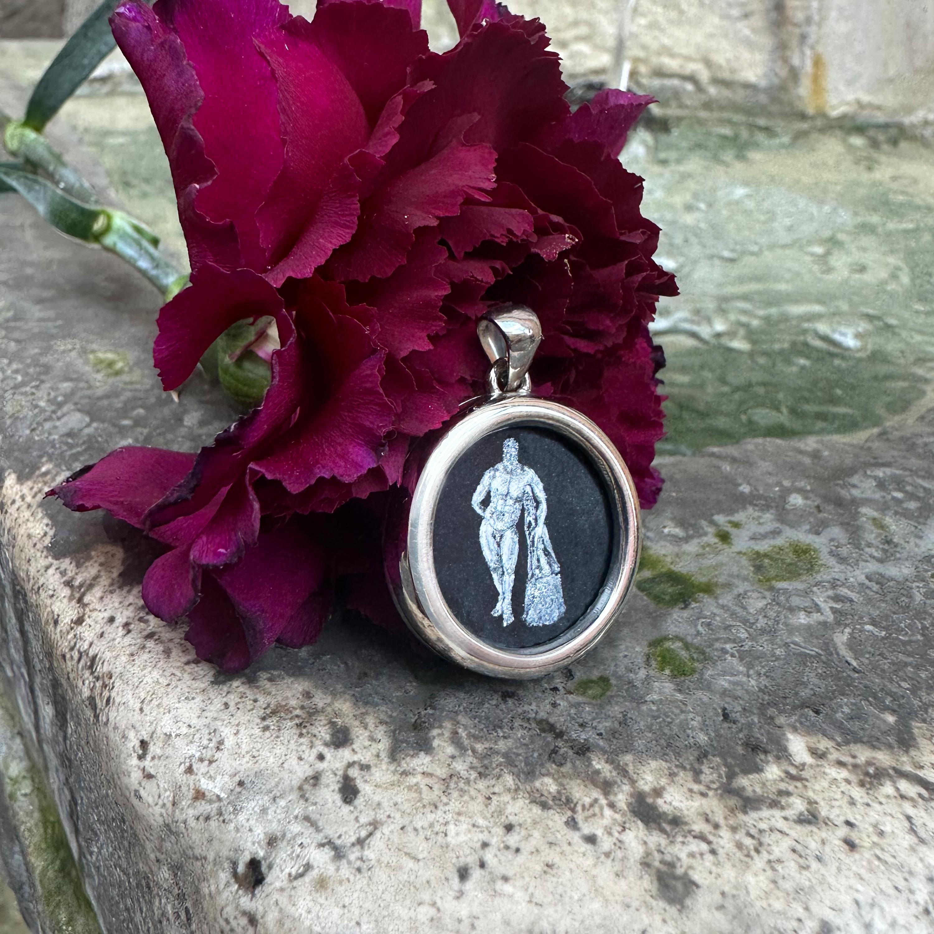 Questo ciondolo presenta una rappresentazione dipinta a mano del mitico eroe Eracle, abilmente realizzata dall'artista Tommaso Rossi su Onice. Incastonato in argento massiccio, celebra Eracle, l'incarnazione della forza e dell'eroismo, spesso